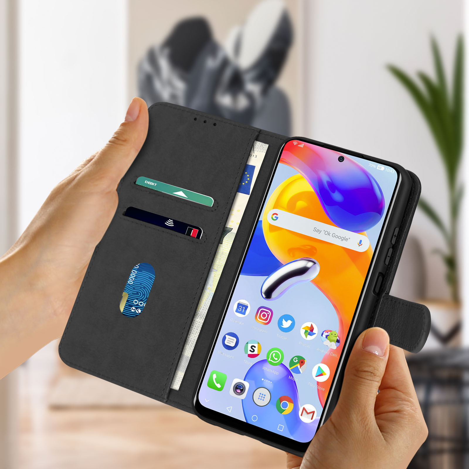 Mani che tengono una custodia nera con telefono all'interno. Carte e denaro visibili.