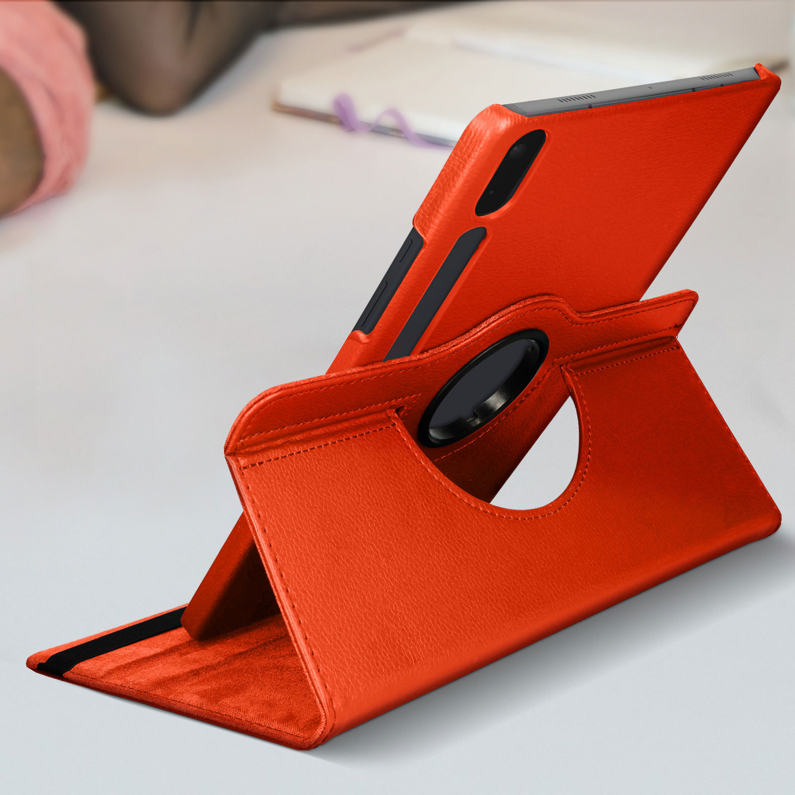 Custodia arancione per tablet in un supporto. Sfondo superficie bianca.