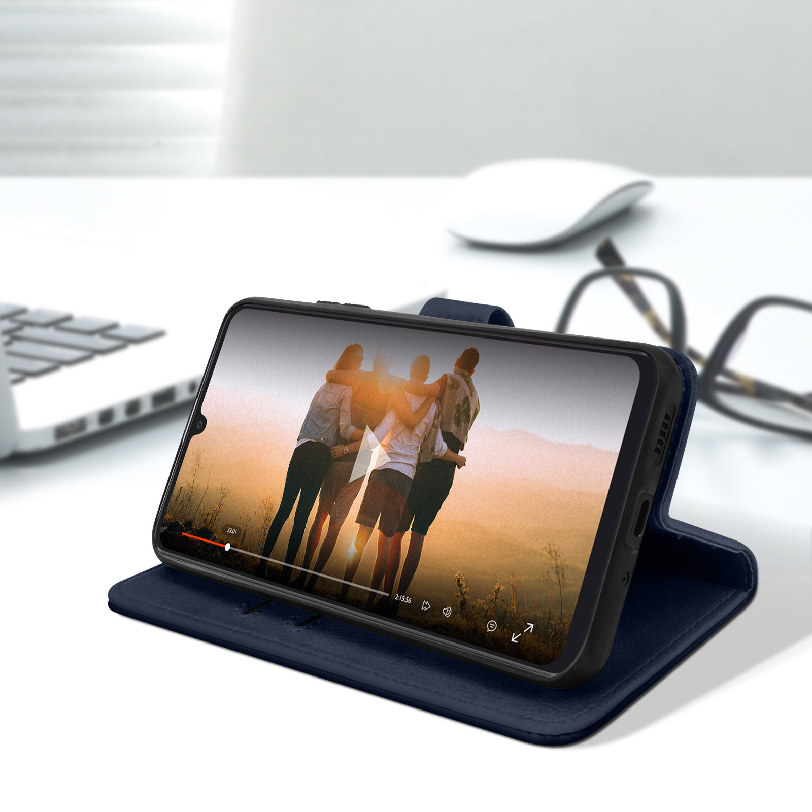 Smartphone in custodia blu, mostra video. Laptop e occhiali visibili.