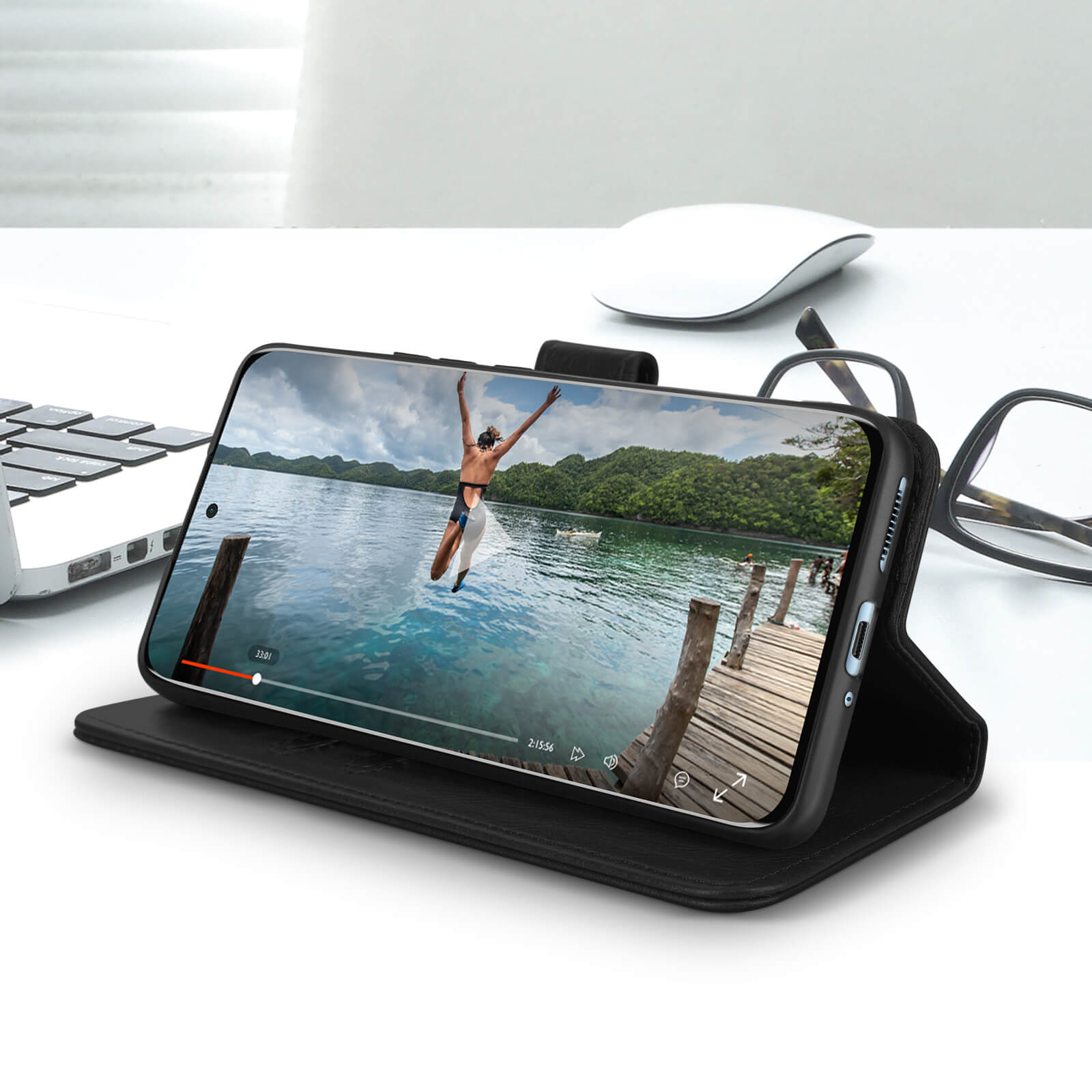 Telefoon met video van persoon die in water springt, op zwarte hoes, op bureau.