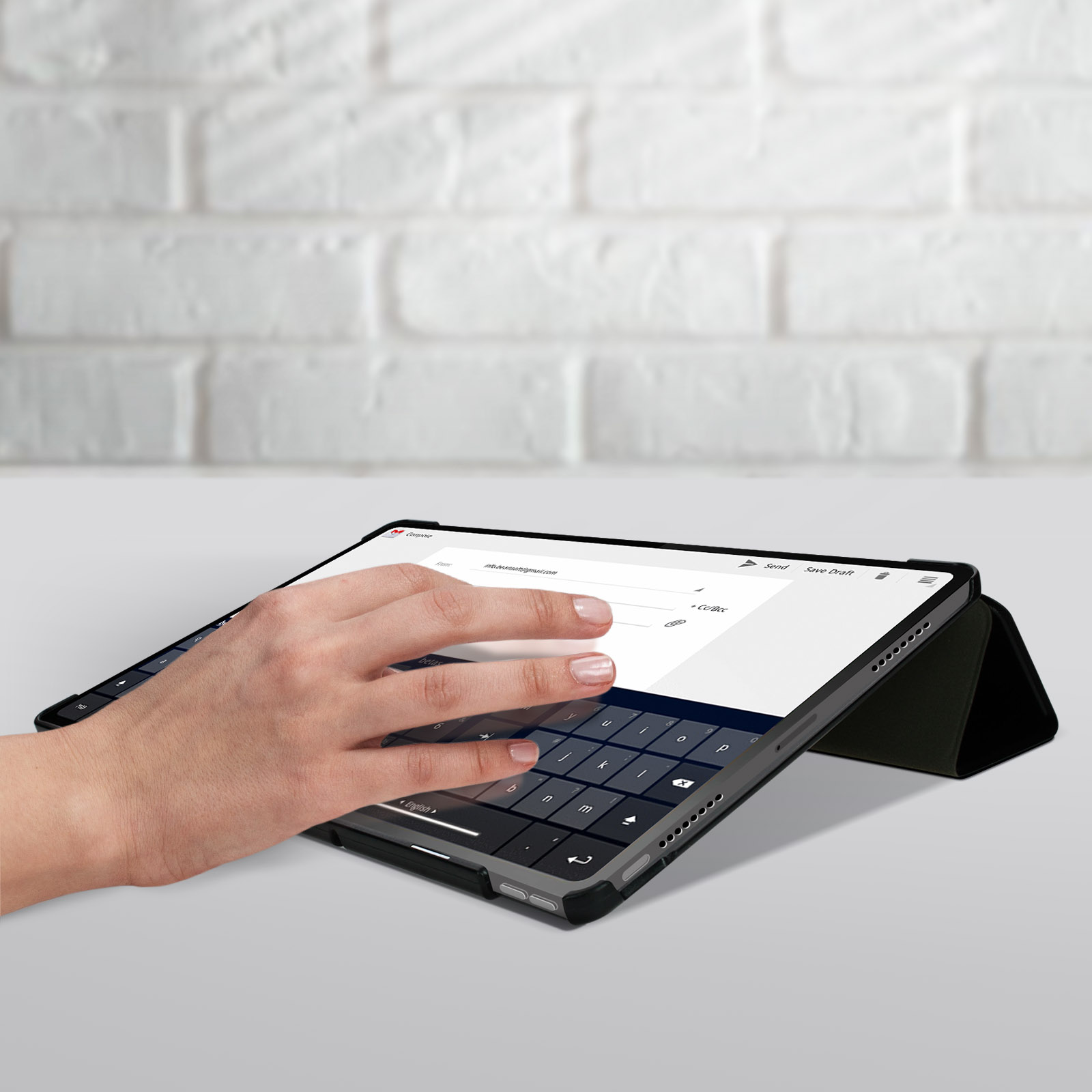 Una persona sta utilizzando una custodia con tastiera nera con un tablet. Il tablet mostra un'interfaccia e-mail.