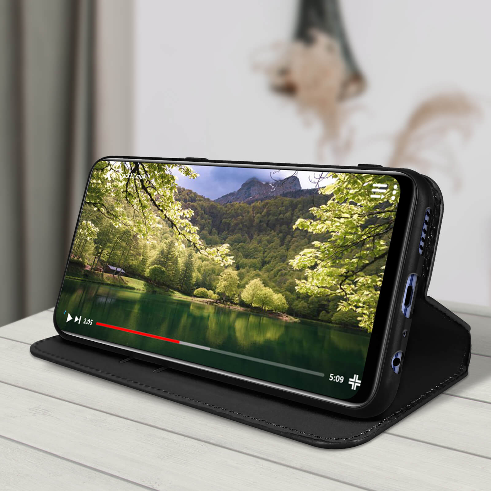 Telefoon toont een meer. Het zit in een zwarte hoes op een houten tafel. De tijd is 5:09.