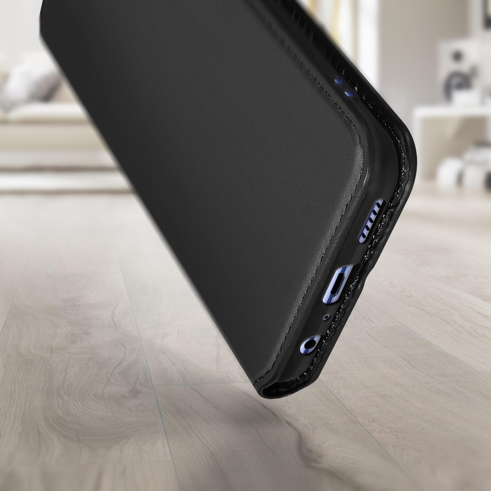 Zwarte telefoonhoes op hout. Schuine opname. Toont de oplaadpoort en de luidspreker.