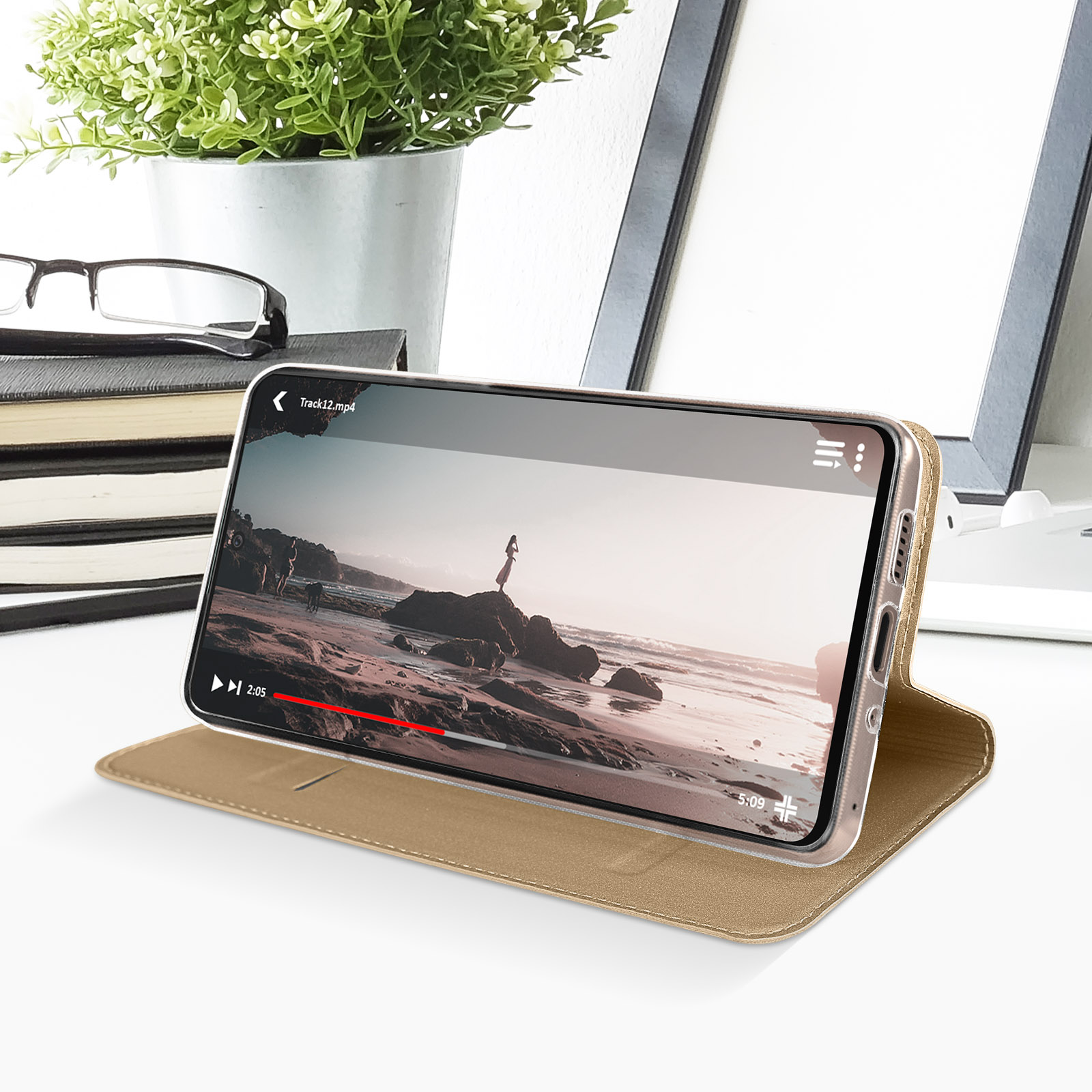 Un telefono dorato in una custodia dorata mostra un video.