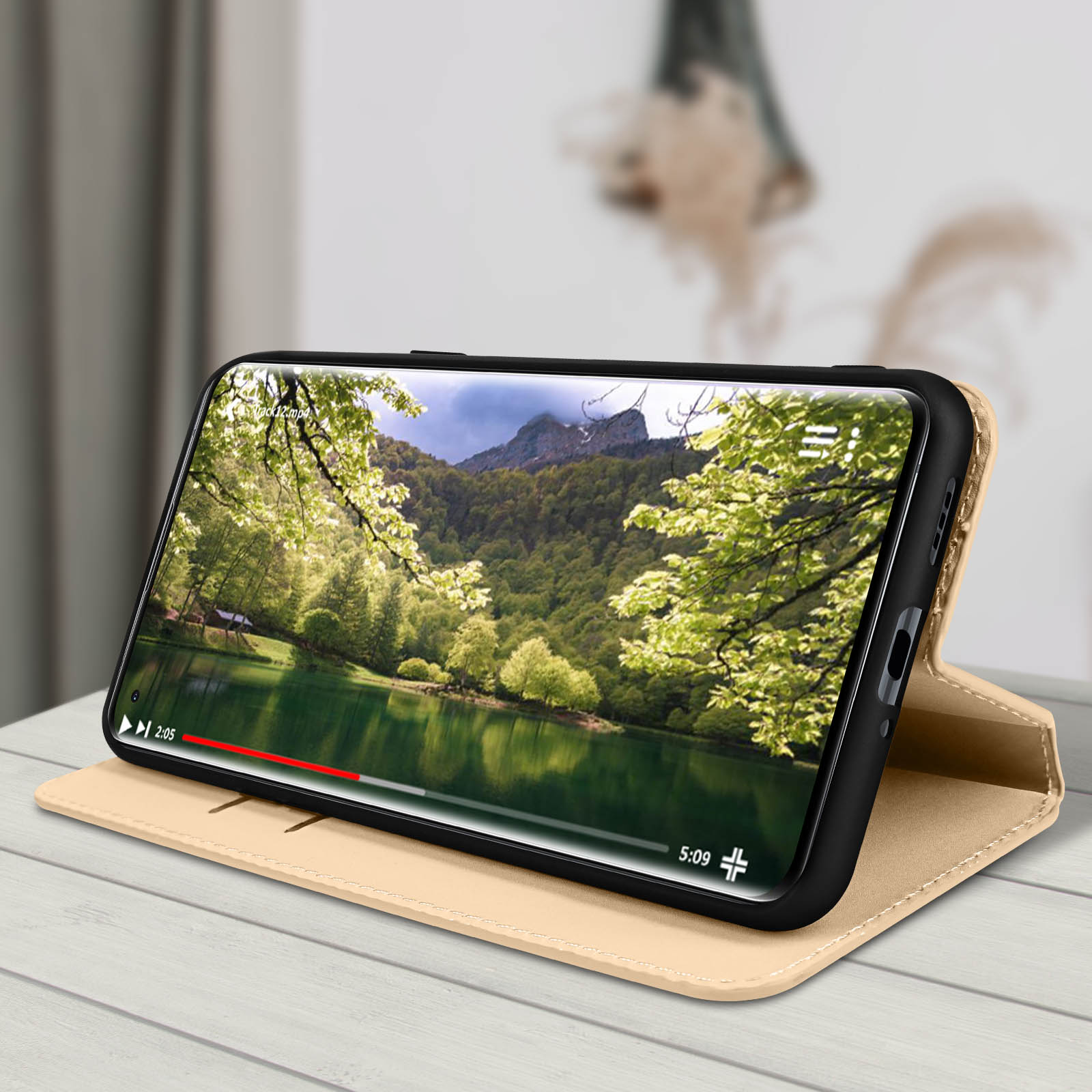 Un telefono in una custodia beige, che mostra un paesaggio di lago e montagna.