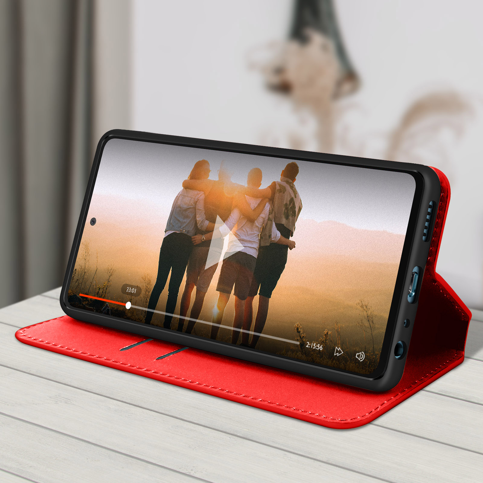 Een rode telefoonportemonnee, open, toont een telefoon die een video afspeelt van mensen die elkaar omhelzen.