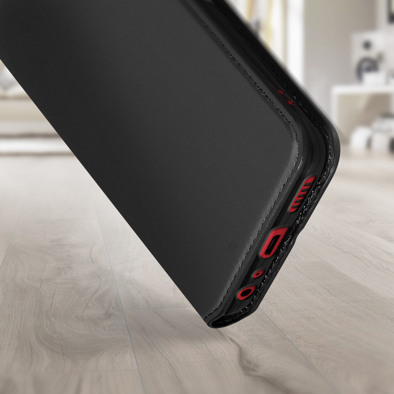 Zwarte telefoonhoes, schuin, met de zijknoppen en rode accenten zichtbaar.