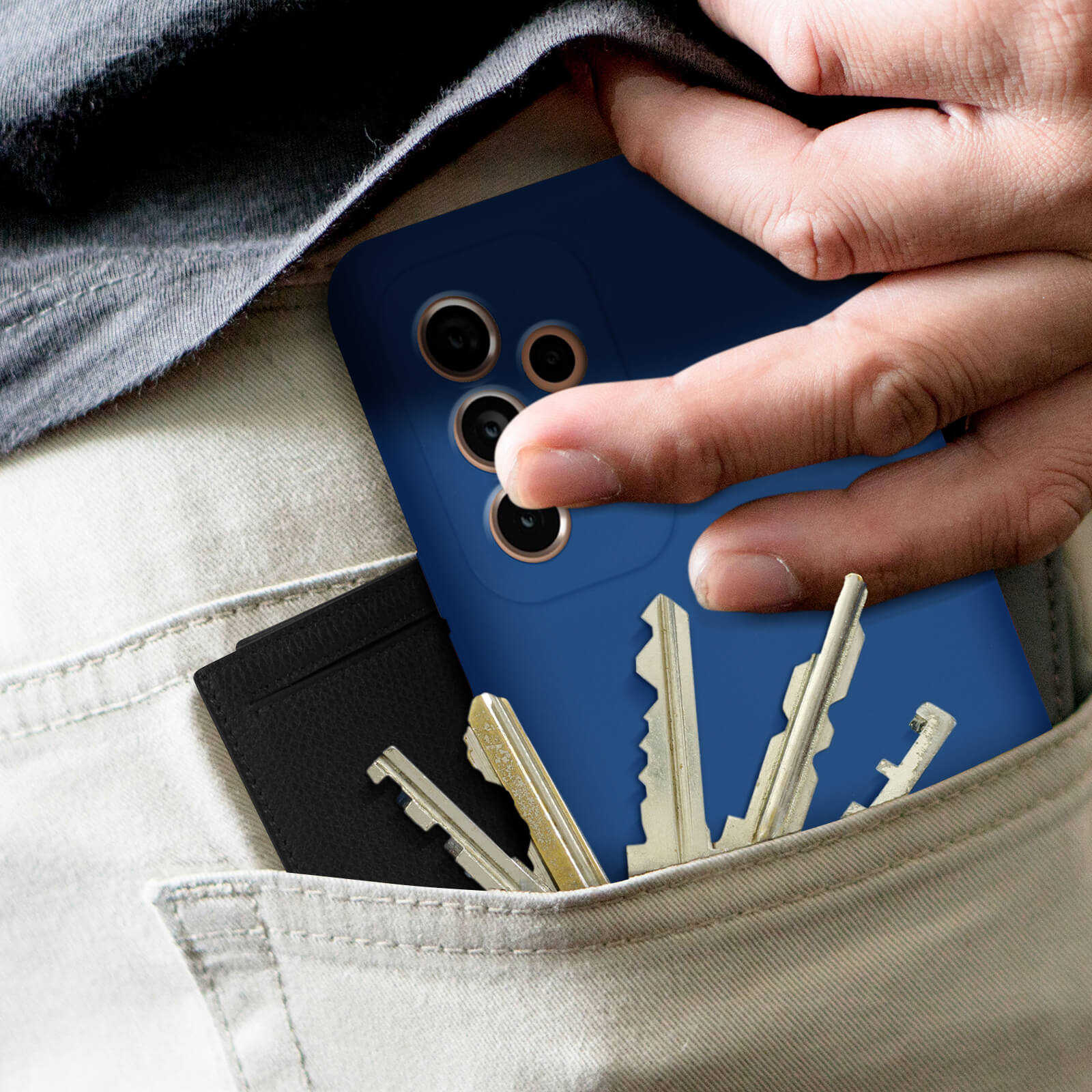 Main dans la poche avec étui de téléphone, clés et portefeuille. L'étui de téléphone est bleu.