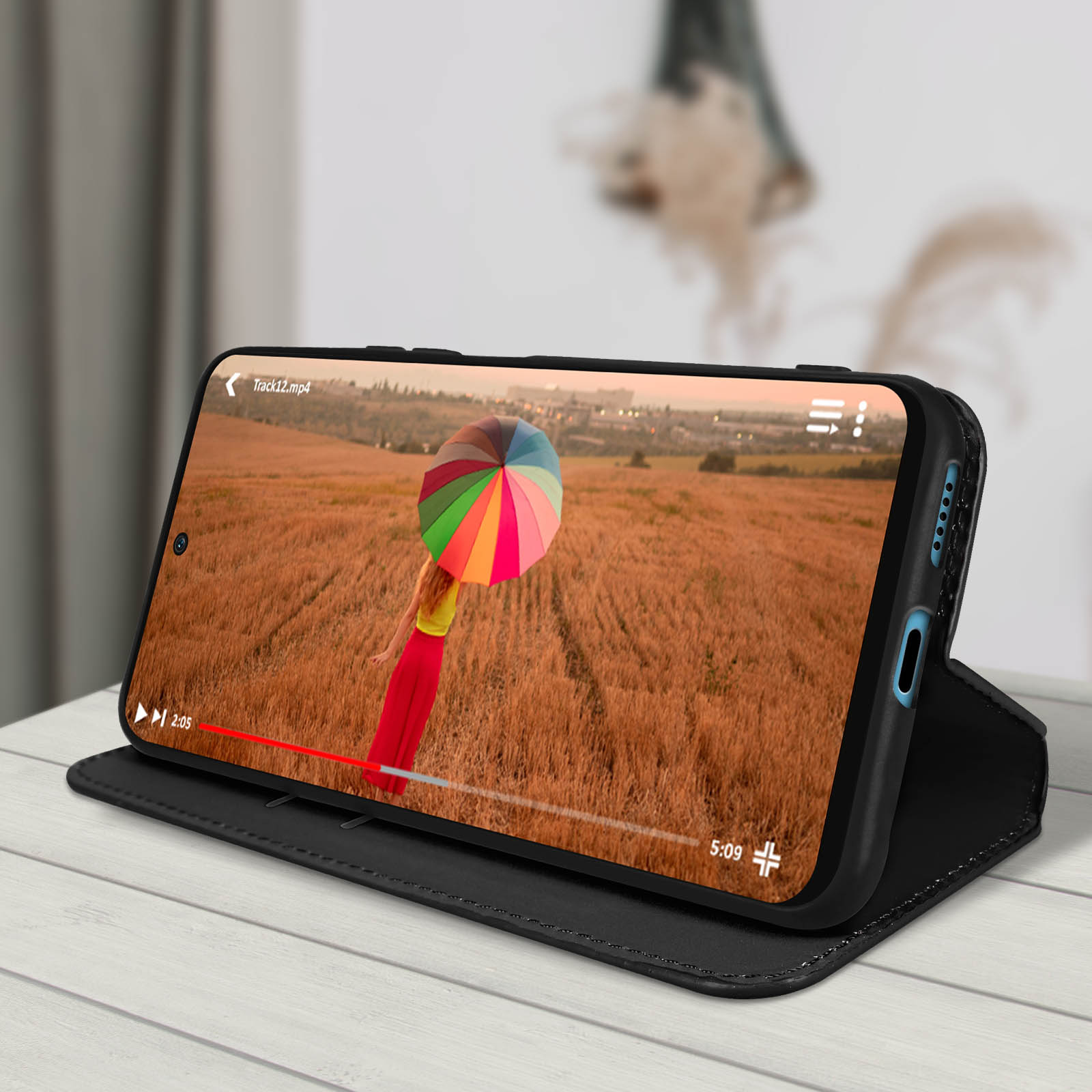 Téléphone dans un étui portefeuille noir, diffusant une vidéo d'une femme avec un parapluie.