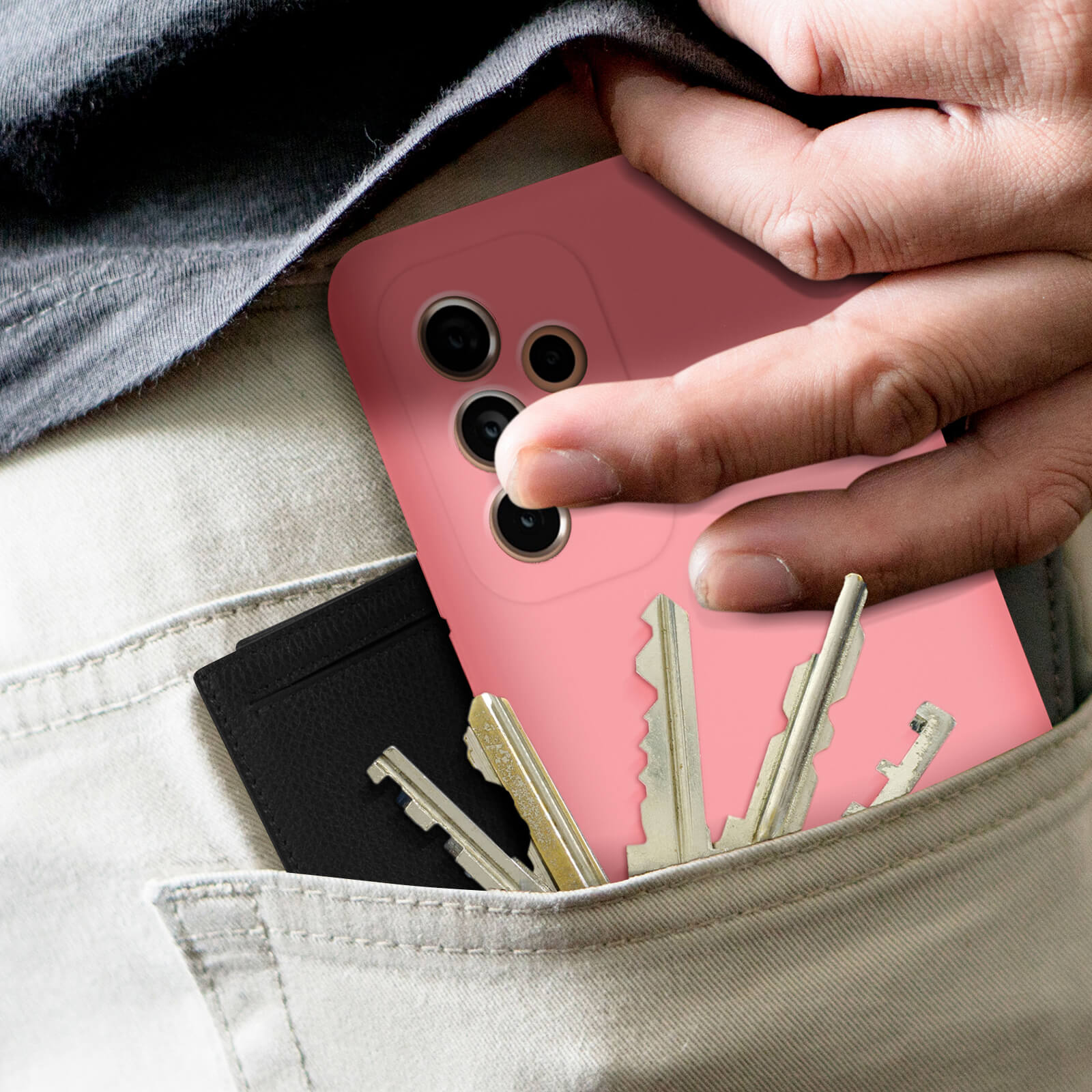Een hand in een zak, met een roze telefoonhoesje, sleutels en een zwarte kaarthouder.