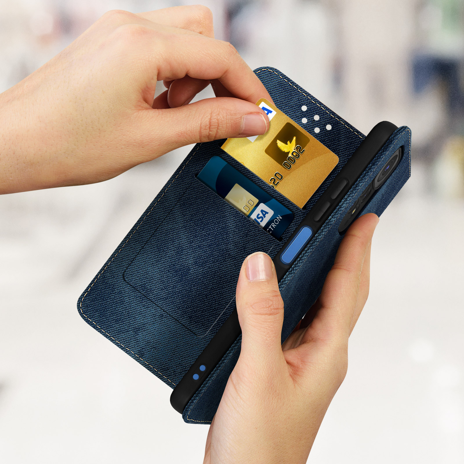 Una mano inserisce una carta d'oro in una custodia per telefono in denim blu con altre carte visibili.