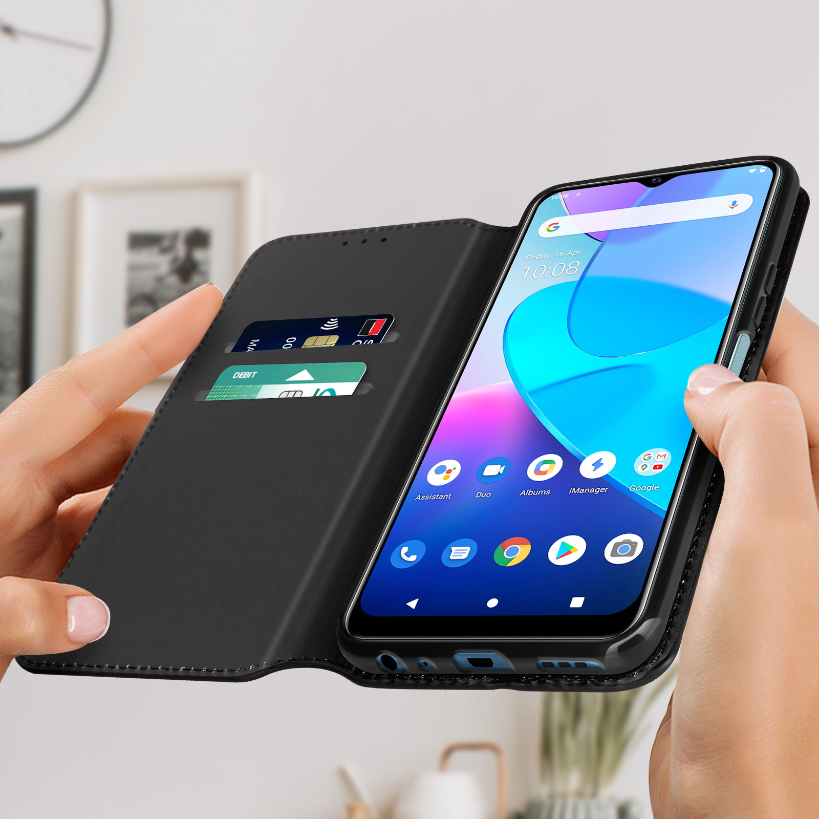 Mani che tengono un telefono in una custodia nera, mostrando una carta di credito e di debito.