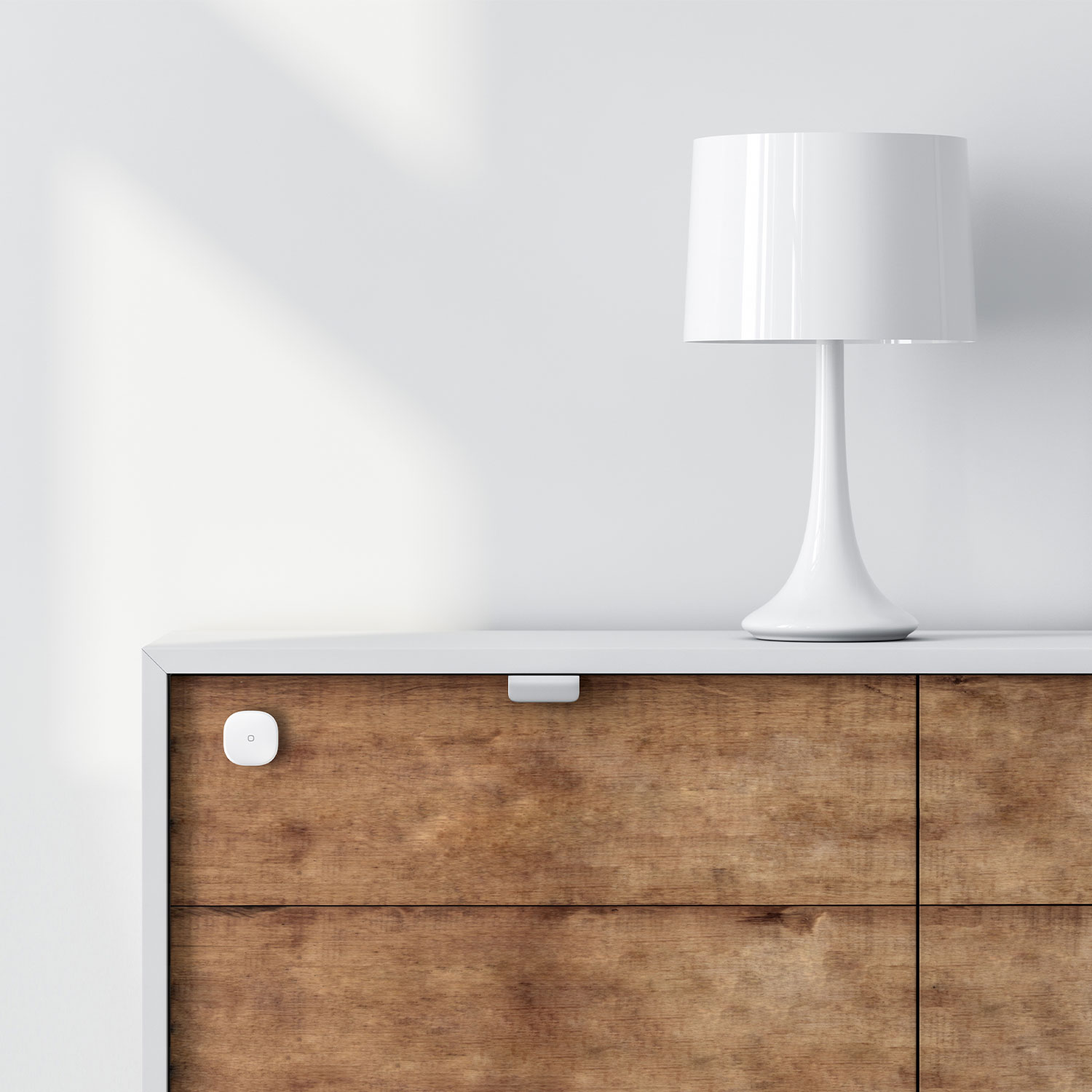 Eine weiße Nachttischlampe und eine Holzschublade mit einem Sensor darauf.
