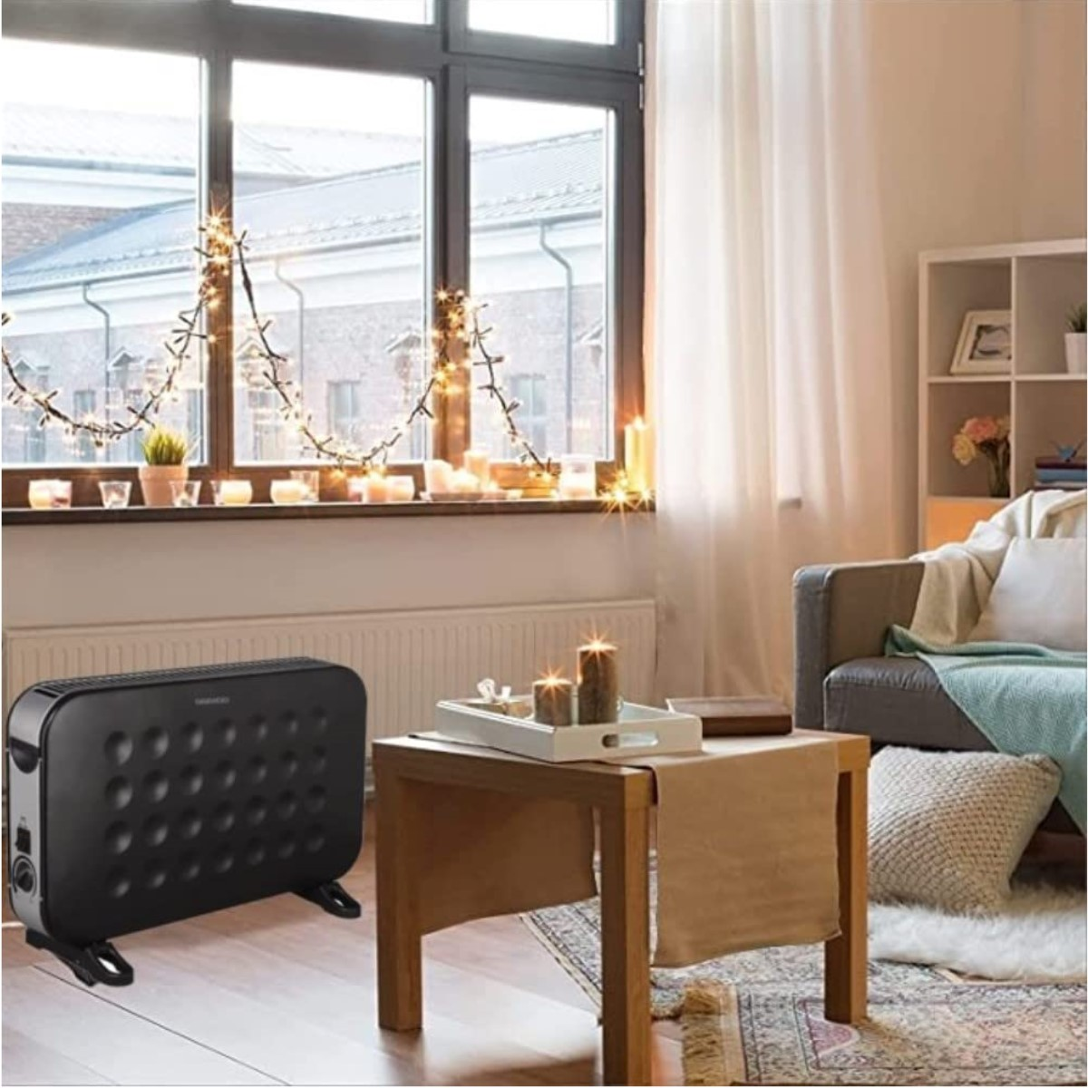 Wohnzimmerszene mit einem schwarzen Heizgerät, Kerzen, einem Sofa und einem Fenster mit Lichtern.