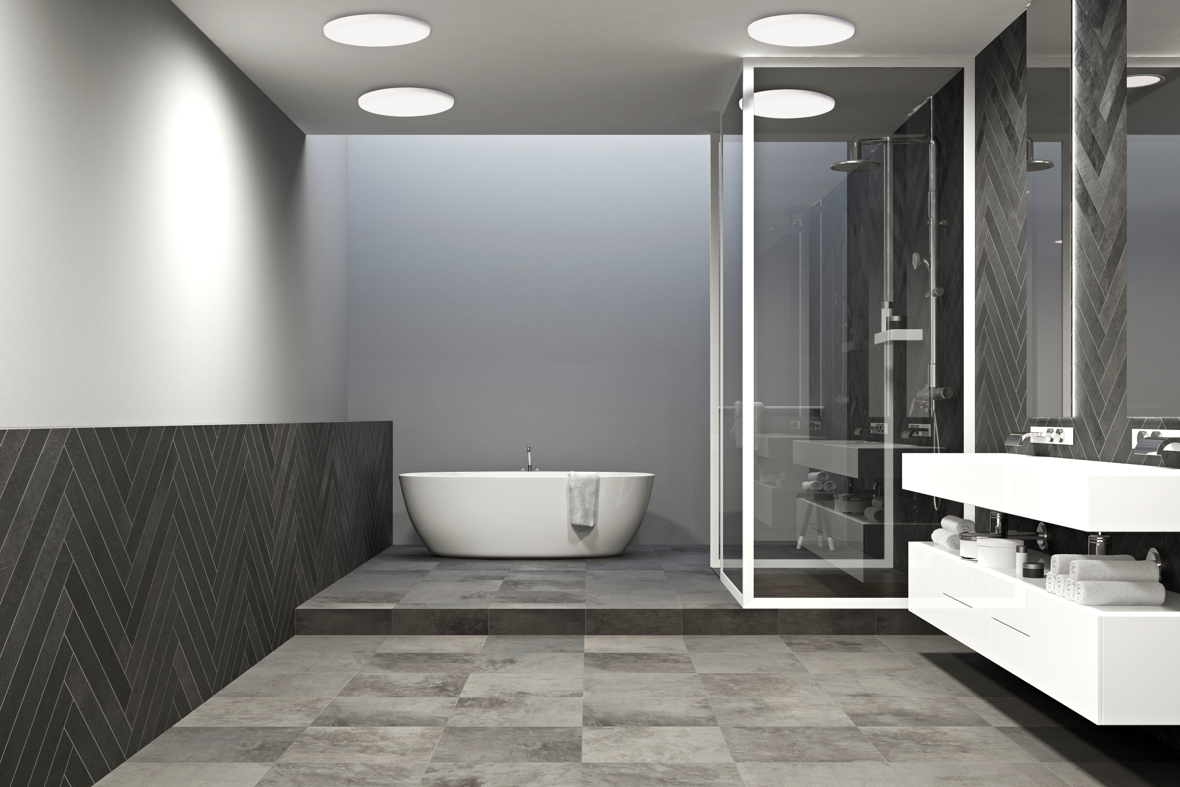 Modernes Badezimmer mit weißer Badewanne, Waschbecken und grauen Fliesenböden und -wänden.