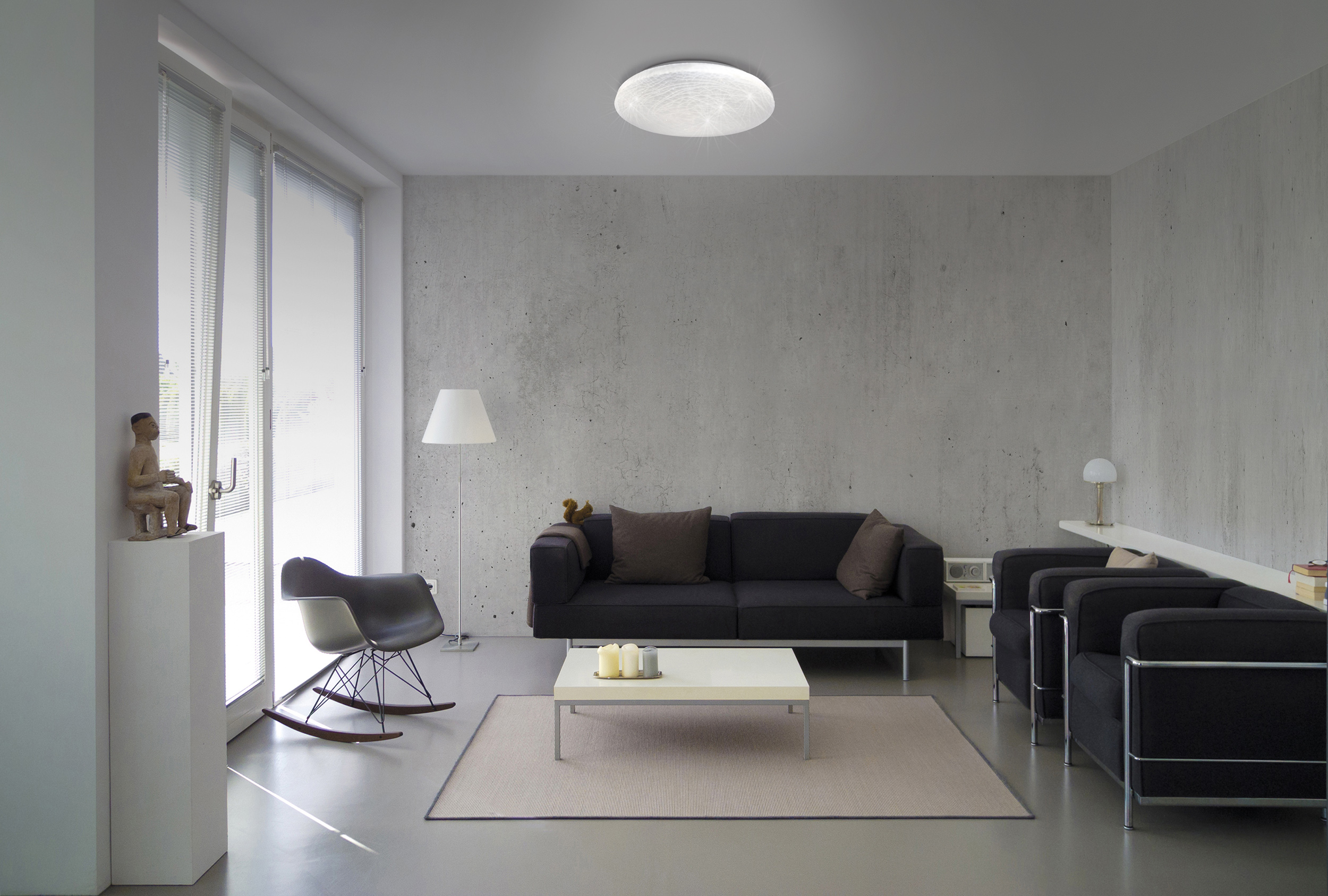 Wohnzimmer mit Möbeln, darunter ein schwarzes Sofa und ein weißer Tisch.