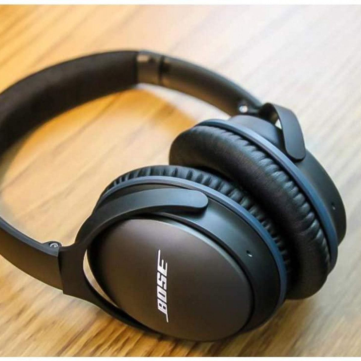 Czarne słuchawki Bose na drewnianej powierzchni, prezentujące logo marki.