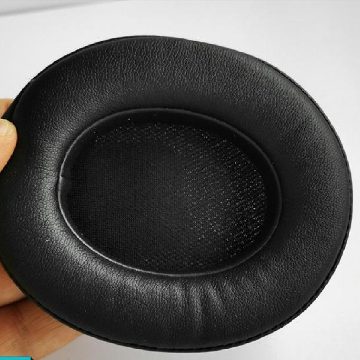 Un coussinet d'oreille noir pour casque, vu de l'intérieur, sur fond blanc.