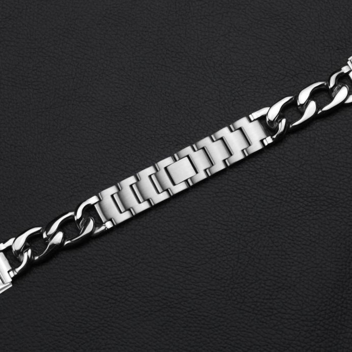 Un bracciale argentato su una superficie nera. Il bracciale ha un design a catena con maglie rettangolari.
