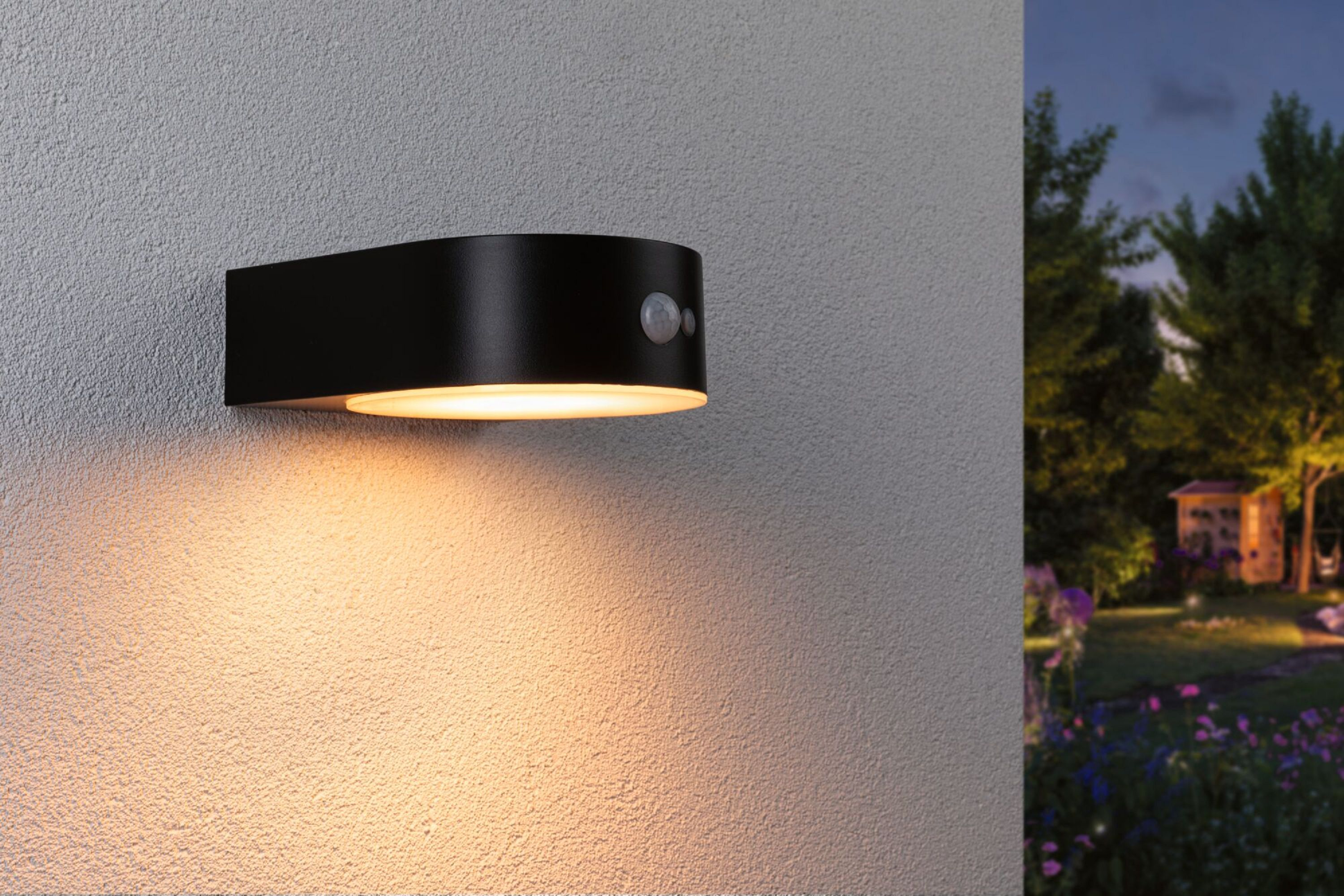 Applique murale extérieure noire. Elle a un design incurvé avec une zone d'émission de lumière et un capteur.