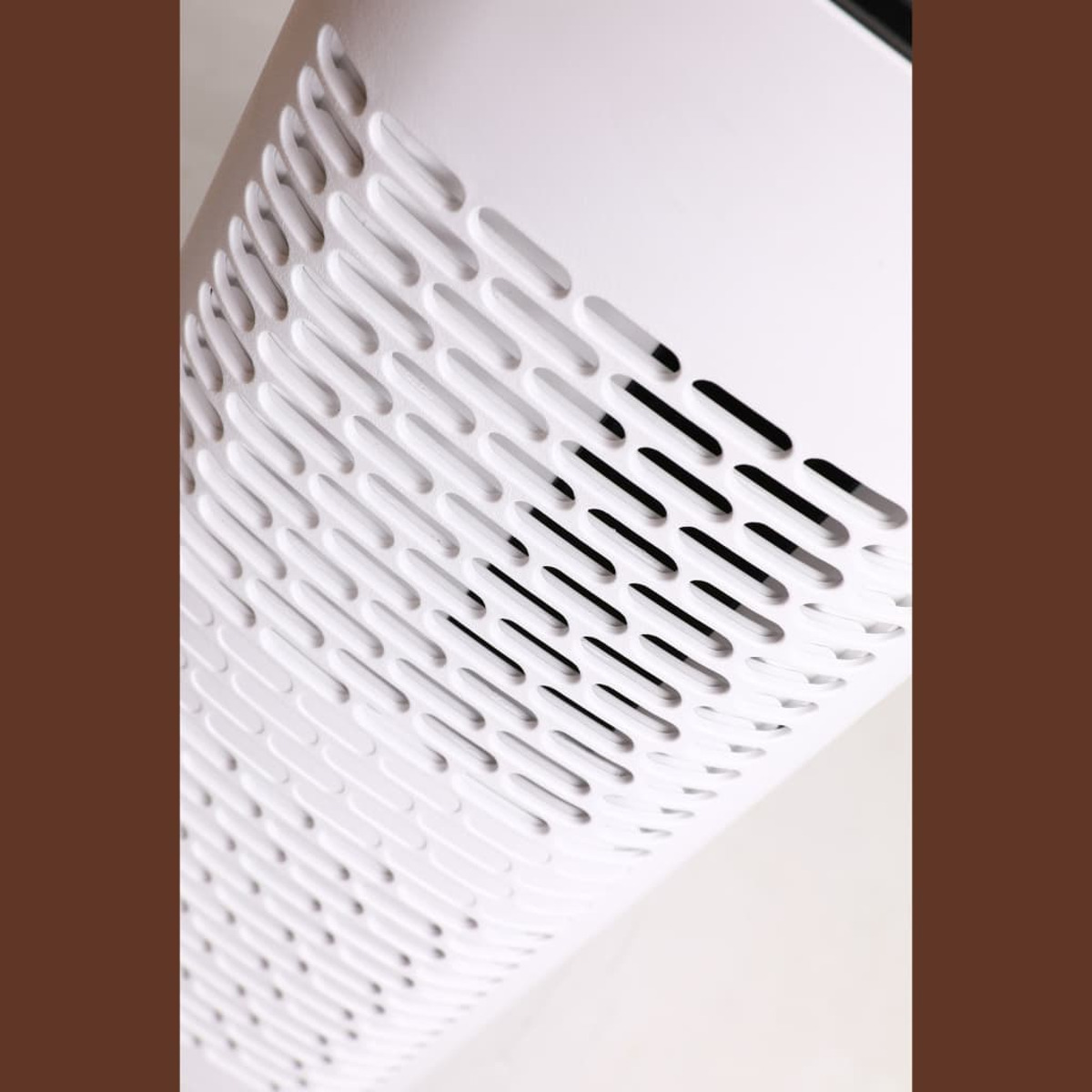 Purificatore d'aria bianco con pannello frontale perforato. Lo sfondo è una superficie bianca.