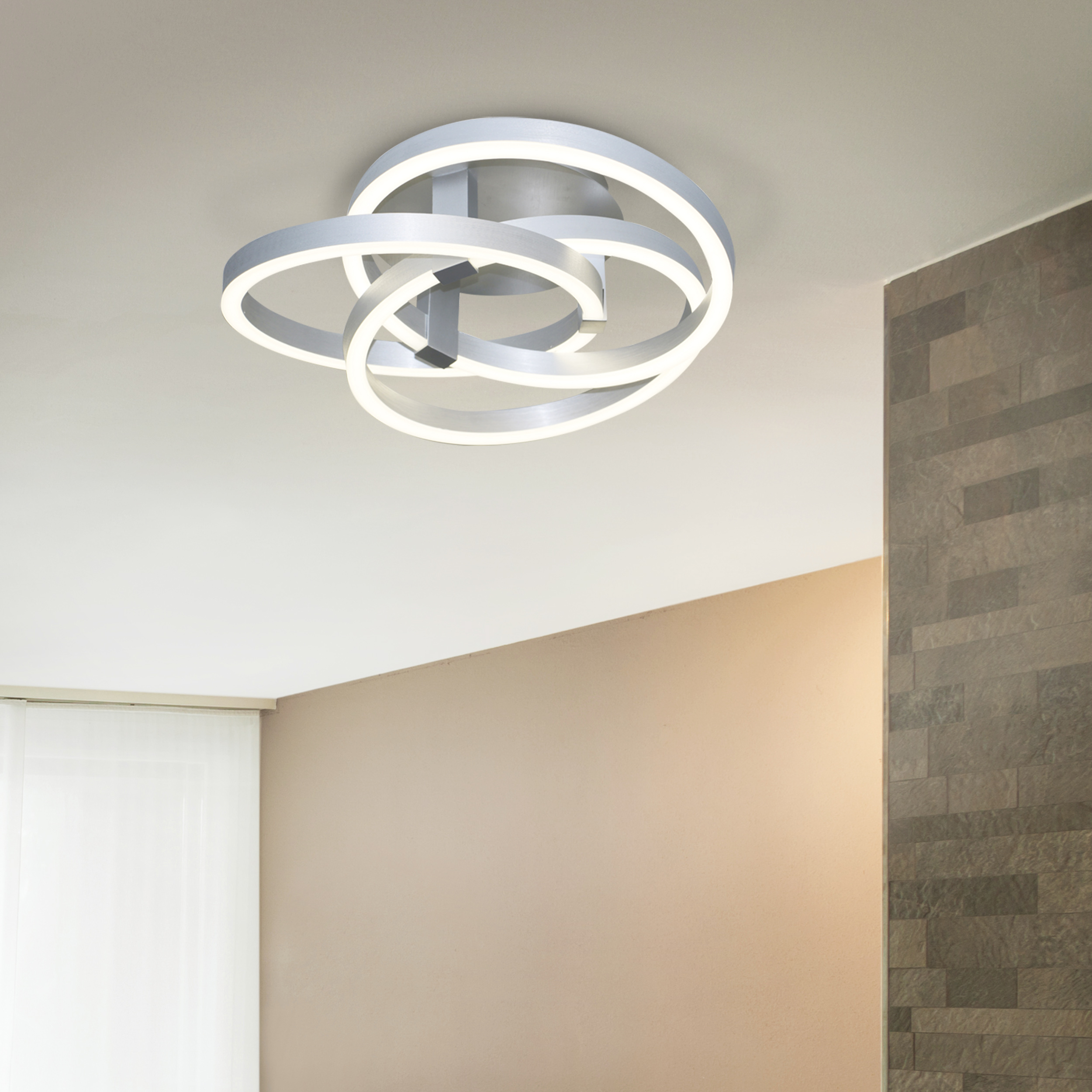 Eine moderne Deckenlampe mit ineinandergreifenden, silberfarbenen, kreisförmigen Leuchten.