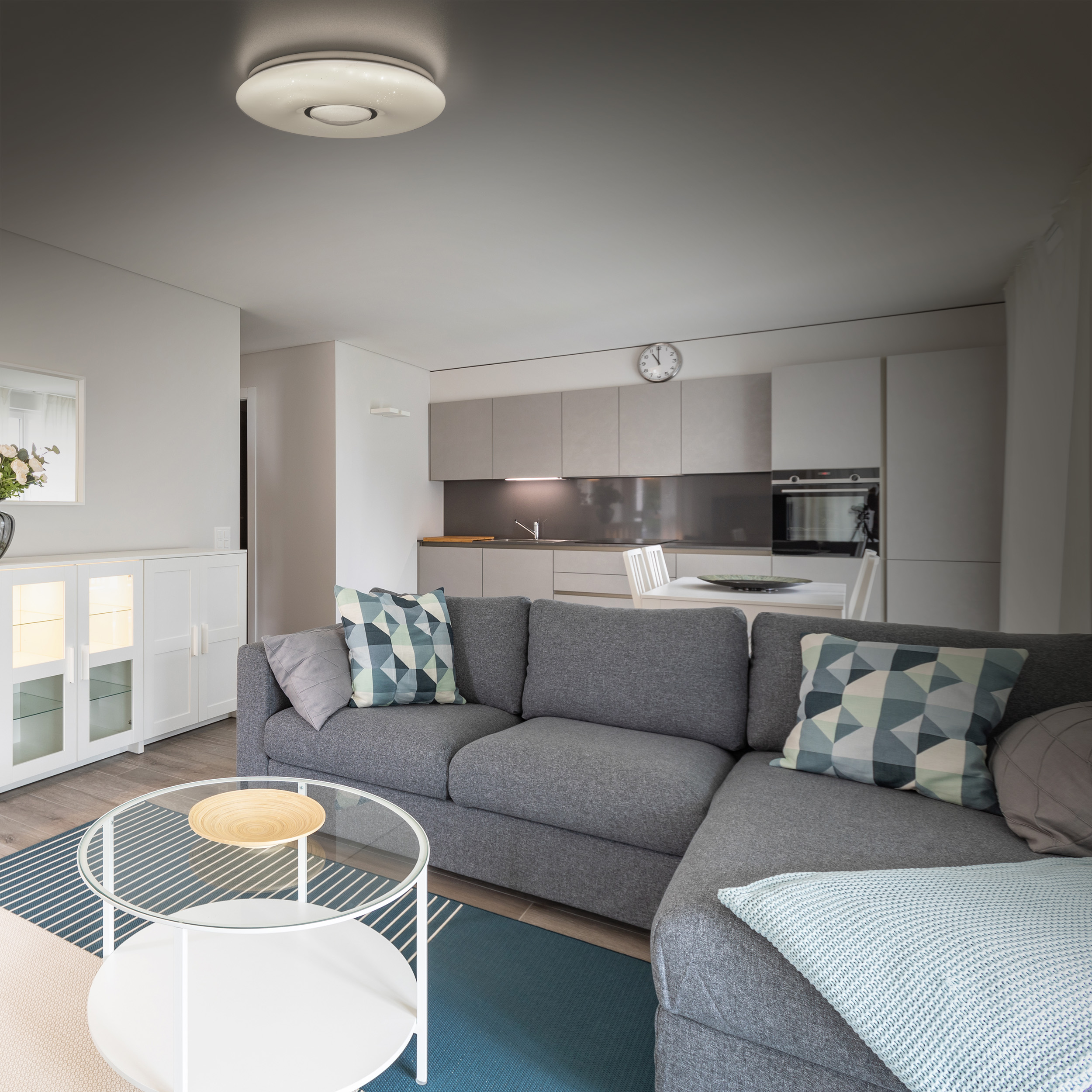 Wohnzimmer mit grauem Ecksofa, Couchtisch und Deckenleuchte. Neutrale Farben.