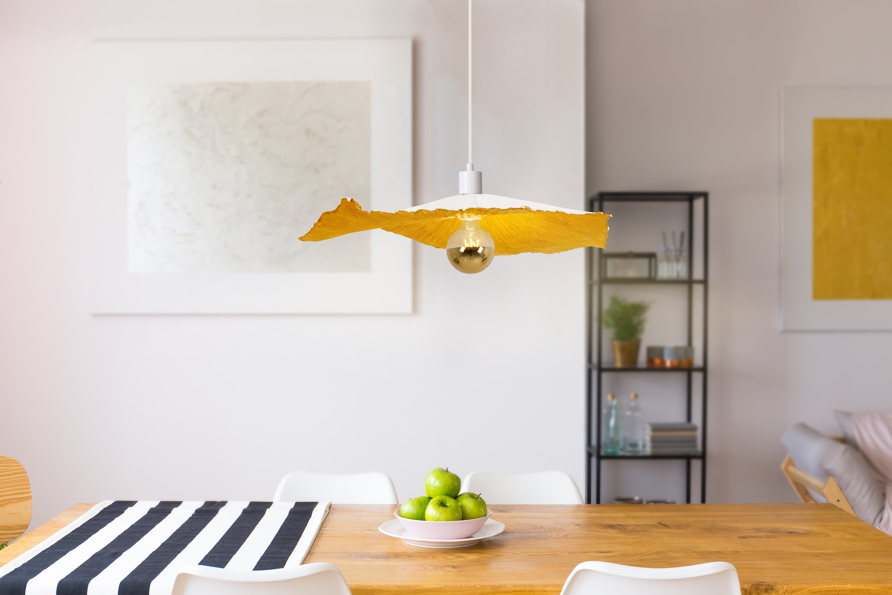 Esszimmer mit Holztisch, Pendelleuchte und grünen Äpfeln.