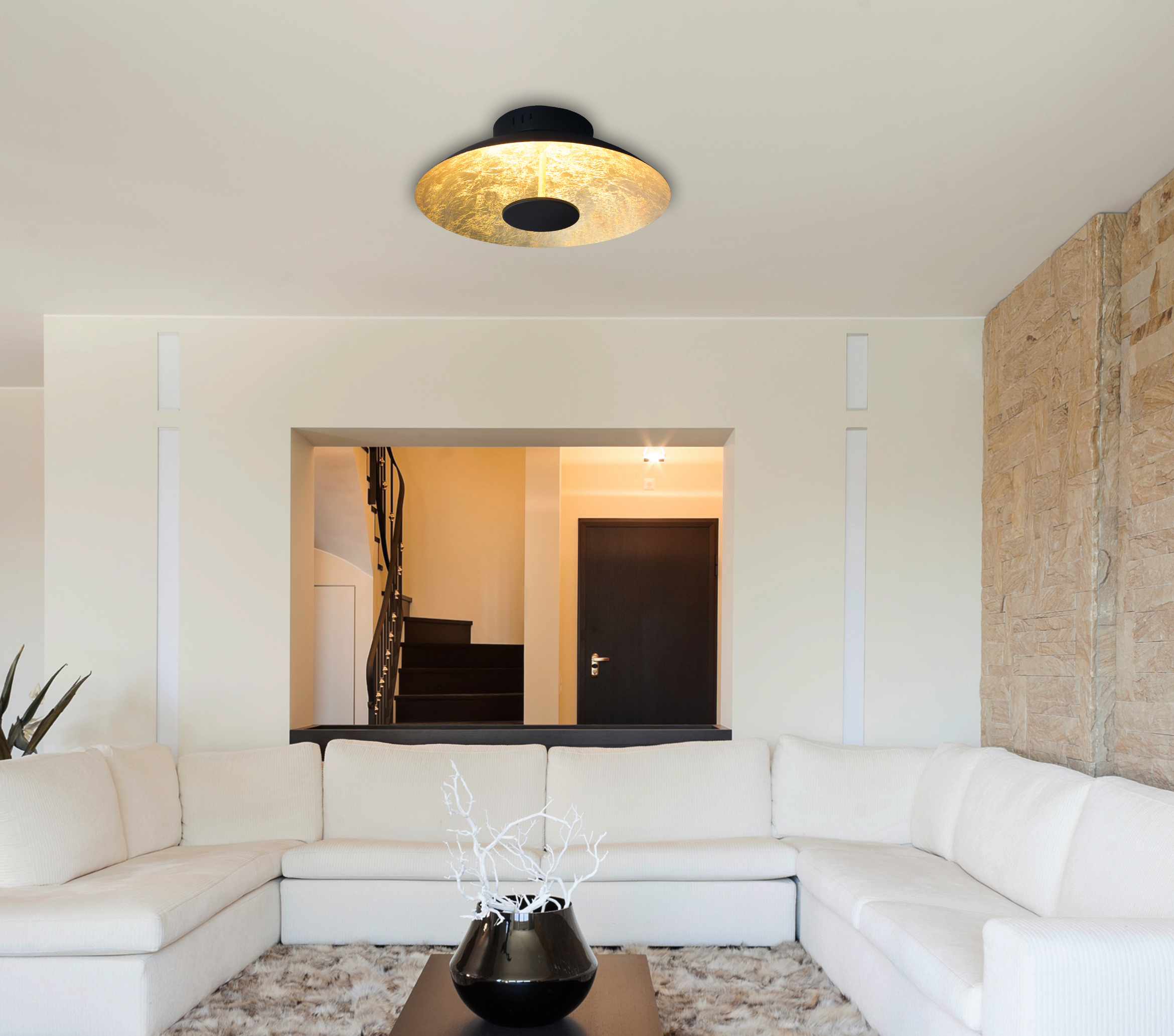 Innenaufnahme eines modernen Wohnzimmers mit goldfarbener Deckenlampe und weißem Sofa.