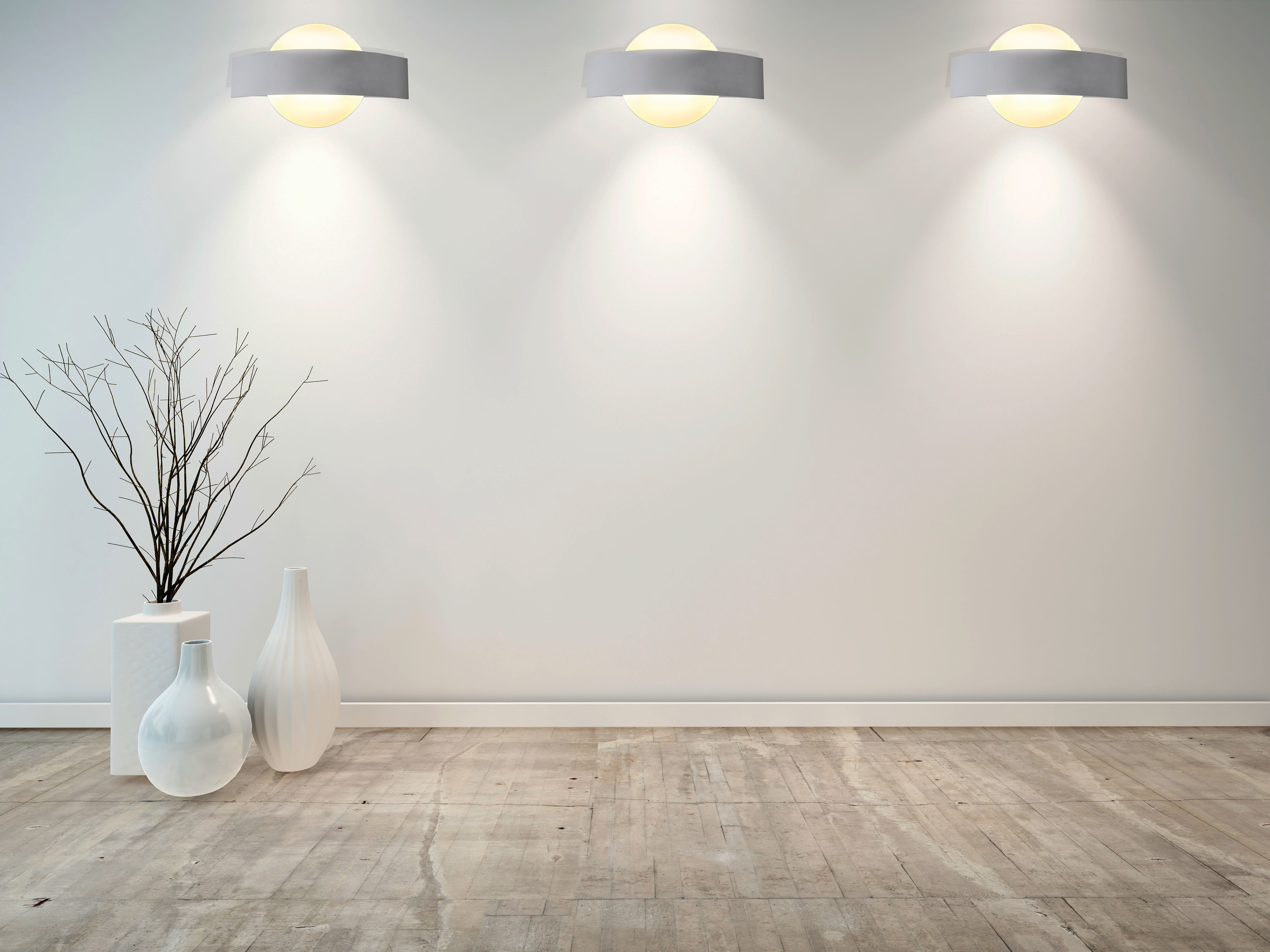 Eine weiße Wand mit drei runden Lichtern, weißen Vasen und einem kahlen Ast auf dem Boden.