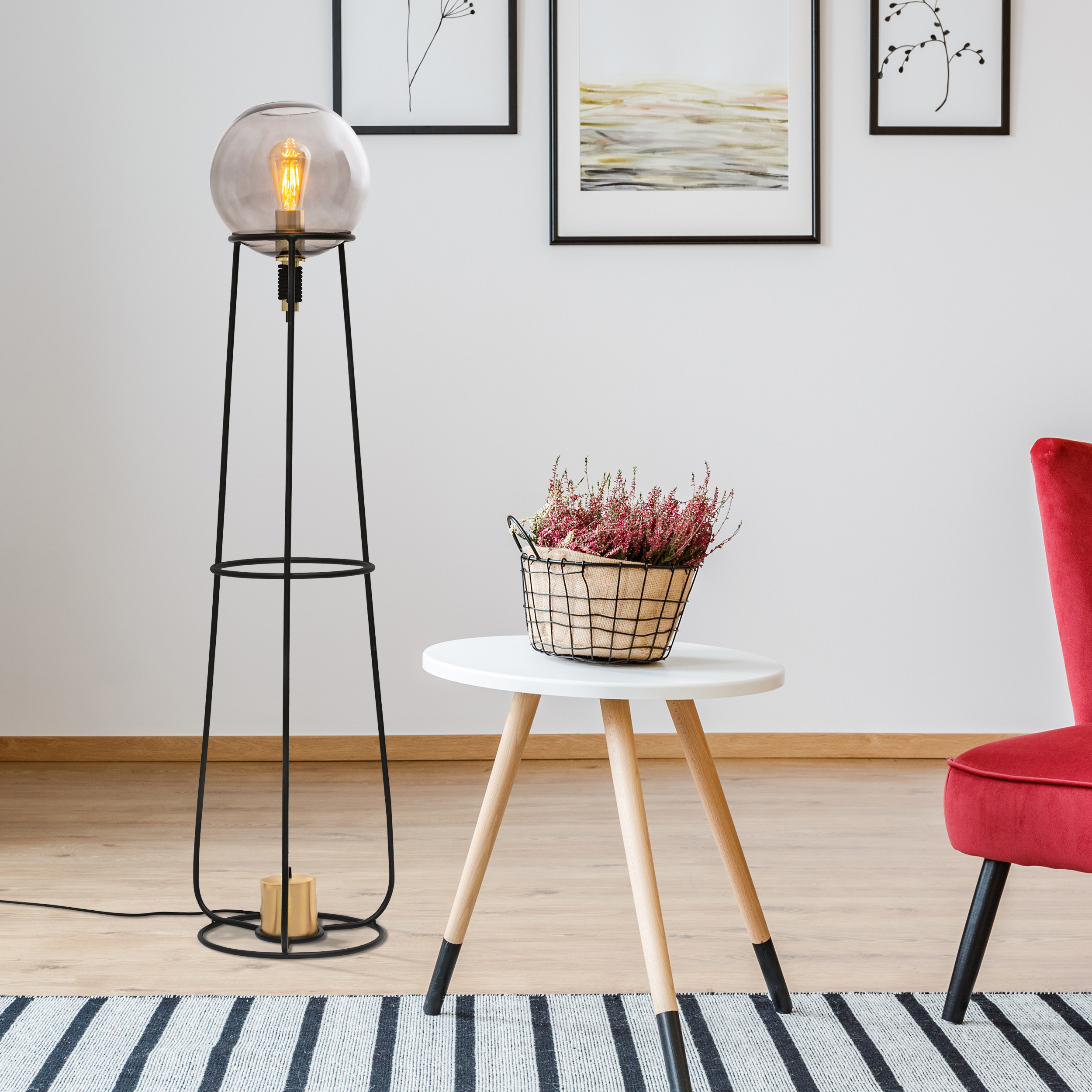 Eine Stehlampe mit Glasschirm, ein kleiner Tisch und ein roter Stuhl.