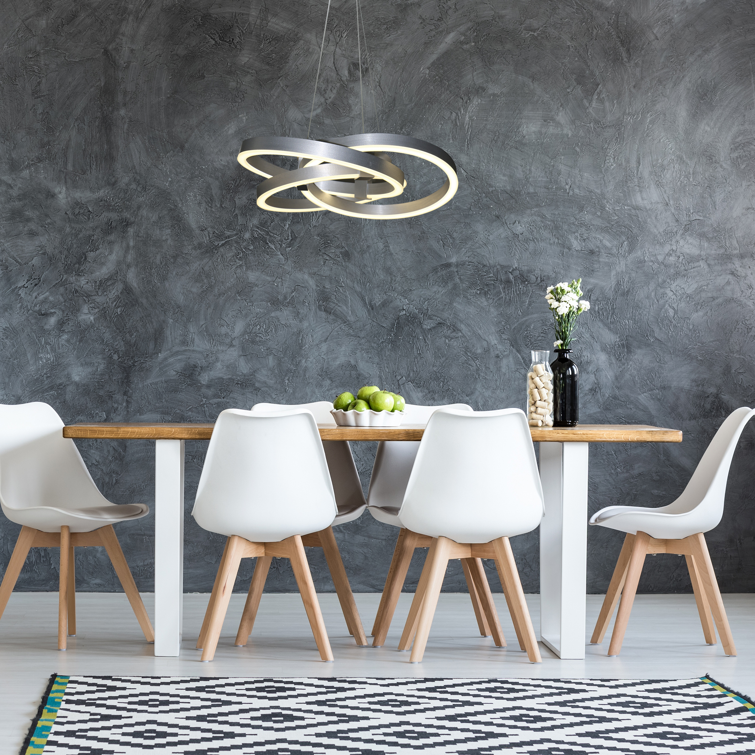 Esszimmer mit langem Holztisch, weißen Stühlen und moderner Deckenleuchte.