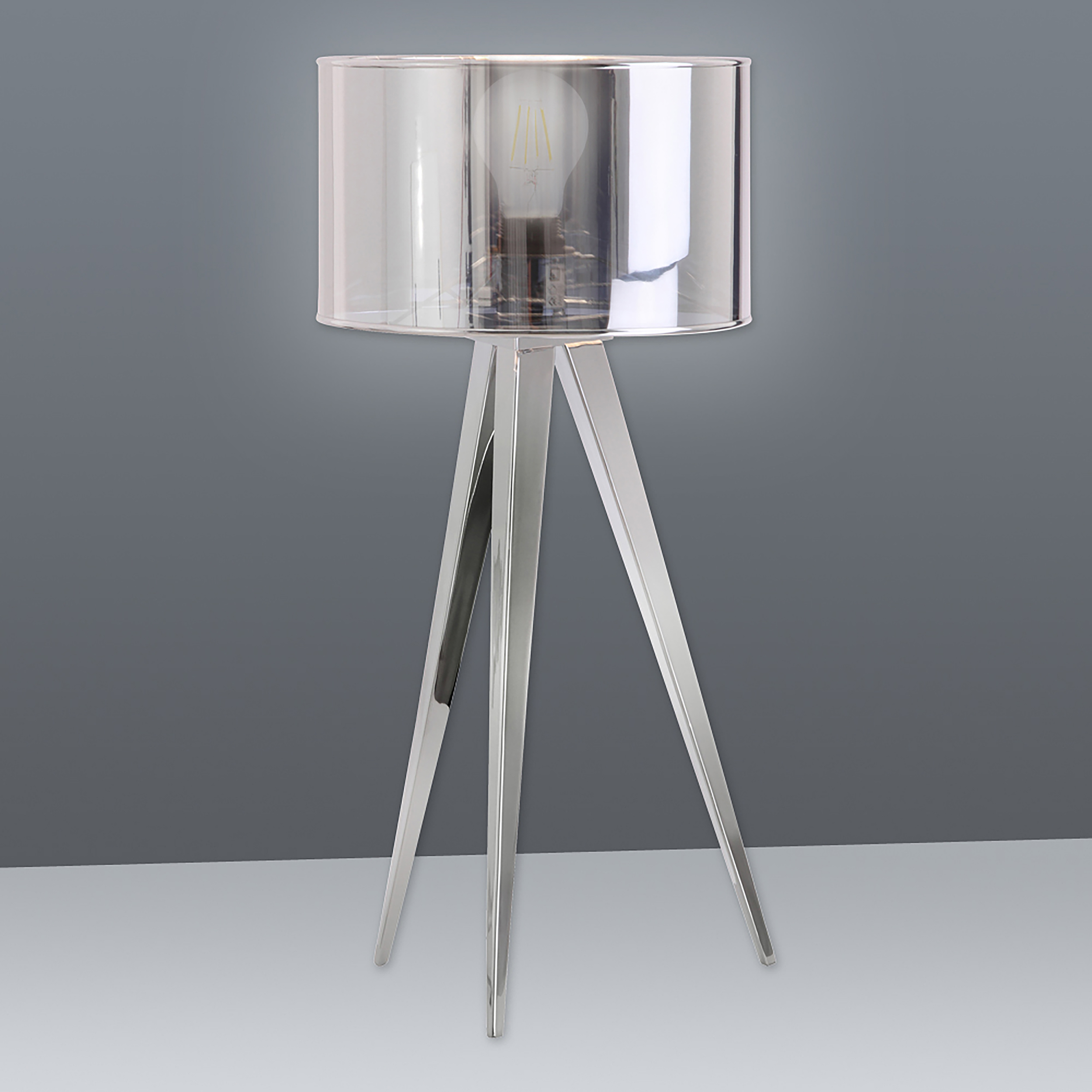 Silberne Stativ-Stehlampe mit transparentem Zylinderschirm und sichtbarer Glühbirne.