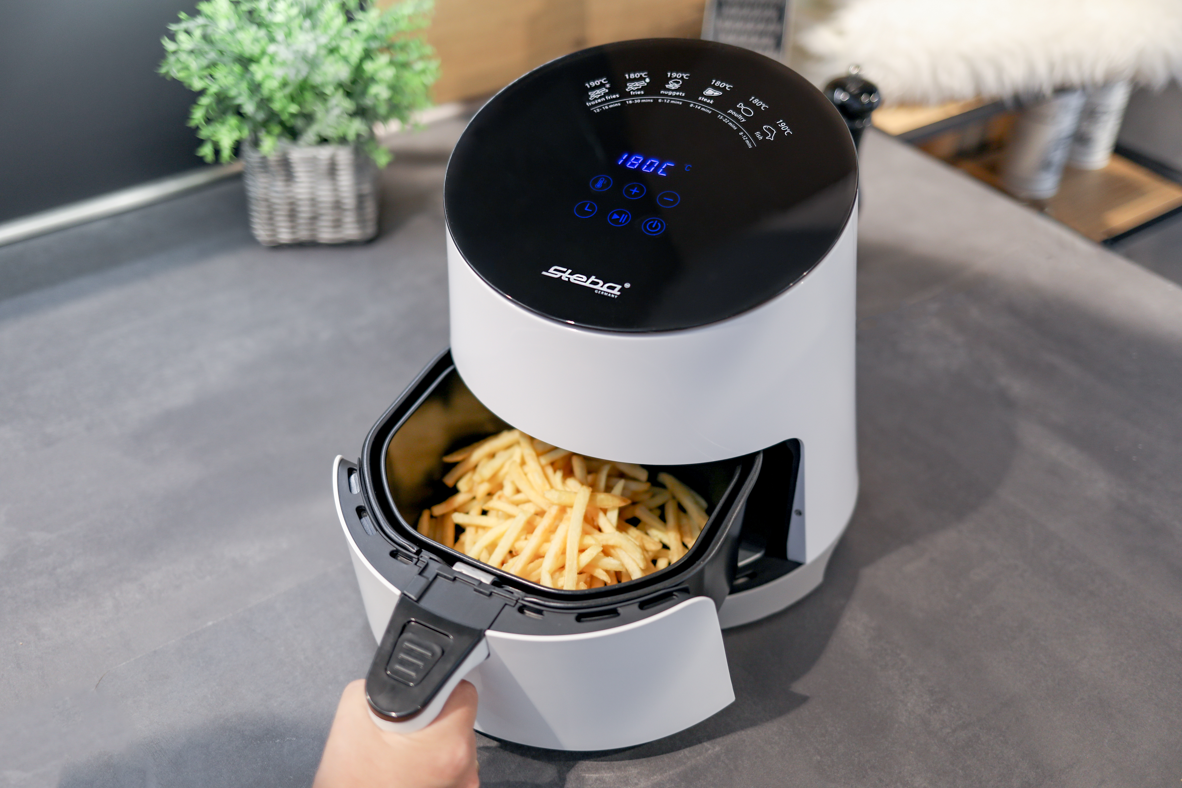 Una friggitrice ad aria con patatine fritte nel cestello.