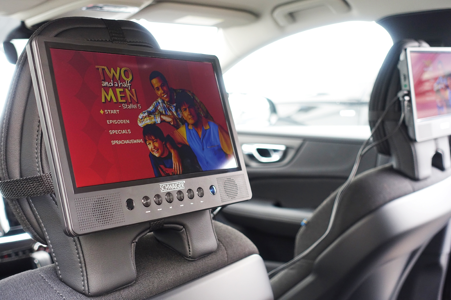Eine Kopfstütze im Auto mit einem Bildschirm, der einen Film zeigt, der die Serie Two and a Half Men zeigt.