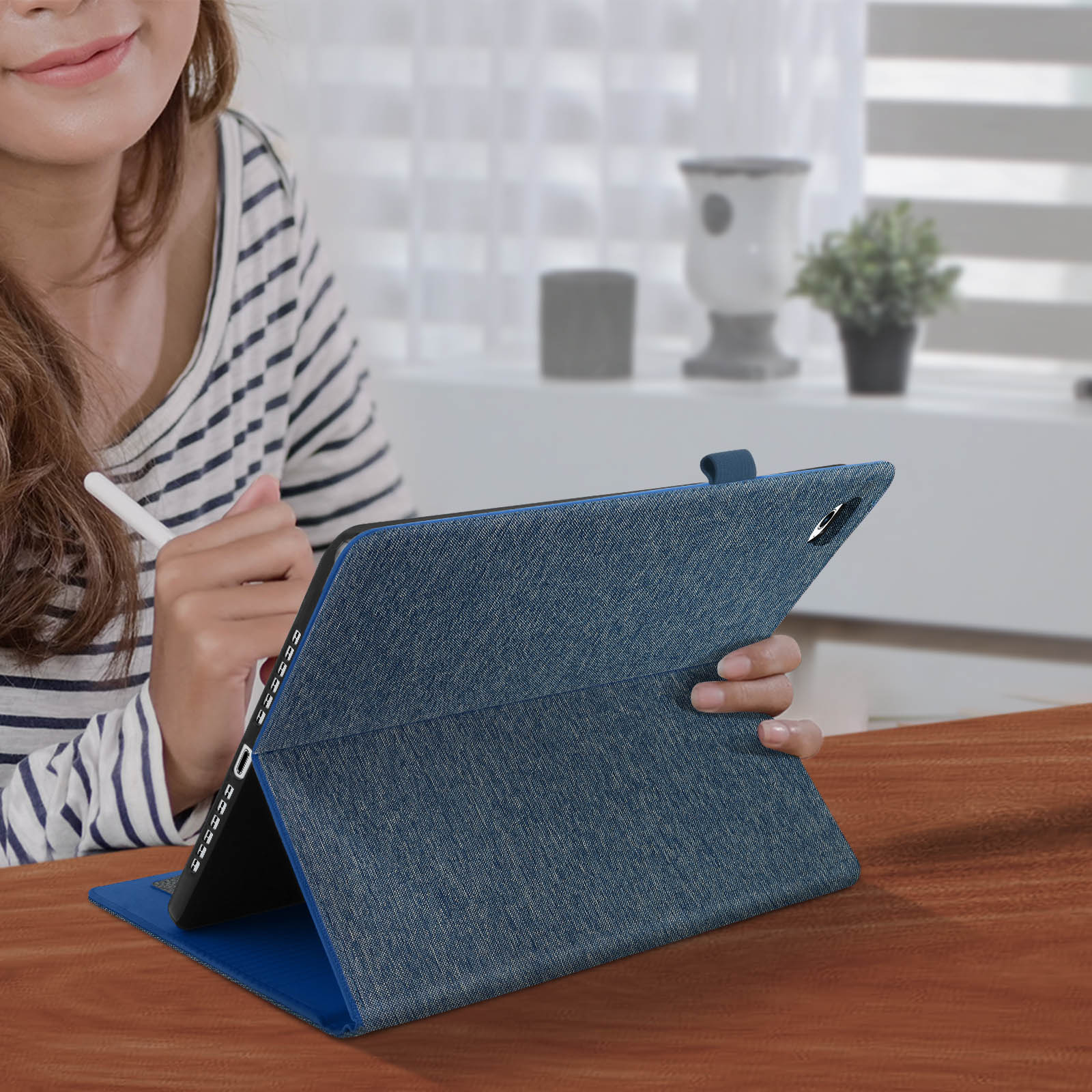 Una donna usa un tablet con una custodia blu, tenendo una penna stilo.