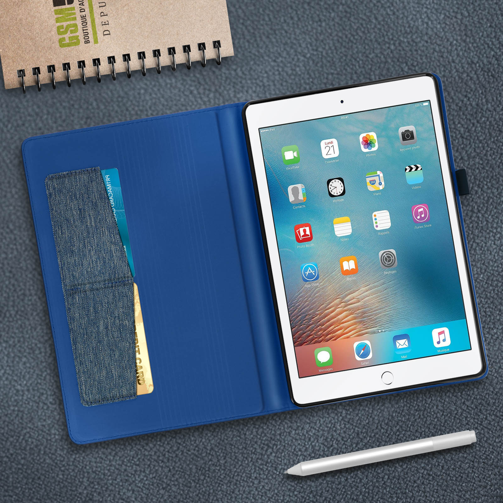 Tablet in custodia blu, penna e blocco note su una scrivania.