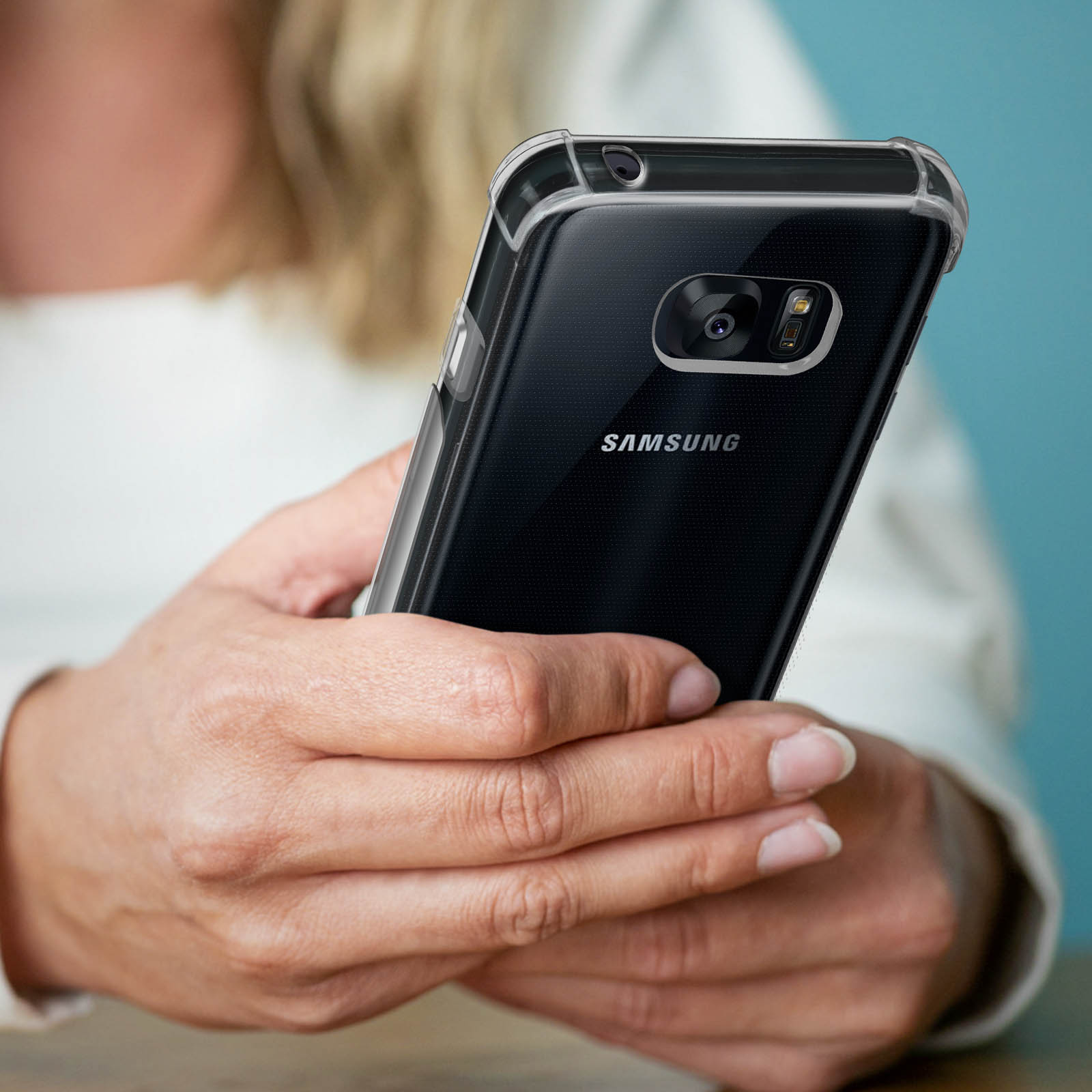 Le mani di una persona che tiene un telefono con una custodia trasparente. Il telefono ha uno schermo nero.