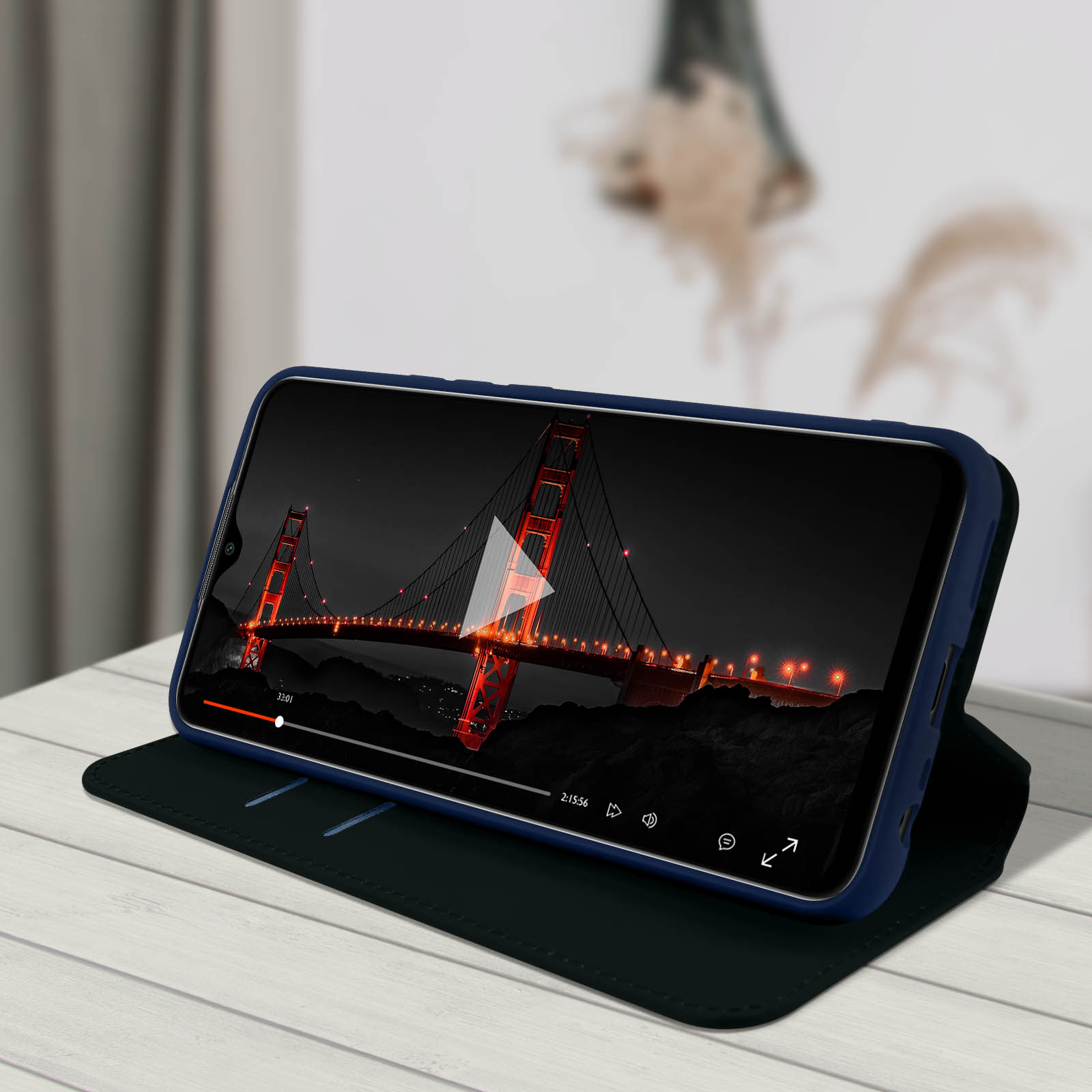 Un téléphone dans un étui bleu affiche une vidéo du Golden Gate Bridge la nuit.