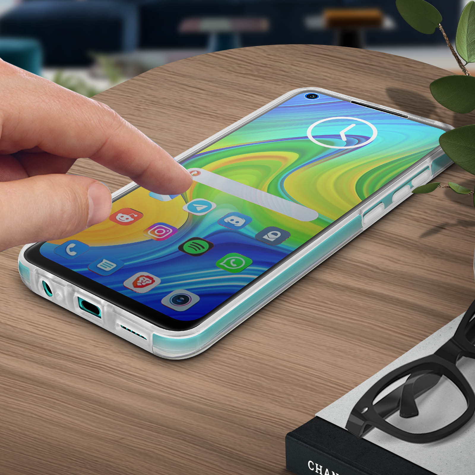 Un doigt touche l'écran d'un téléphone sur une table en bois. Le téléphone affiche des icônes.