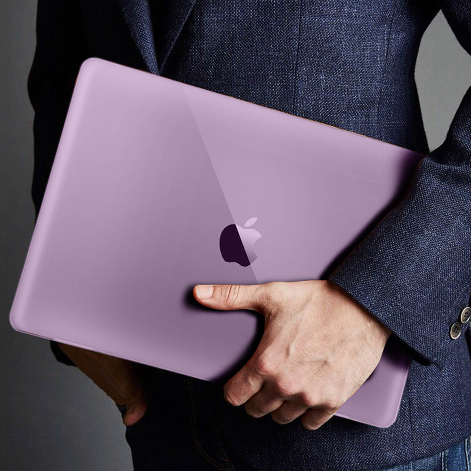 Une personne tient un ordinateur portable violet avec un logo Apple. La personne porte un blazer bleu marine.