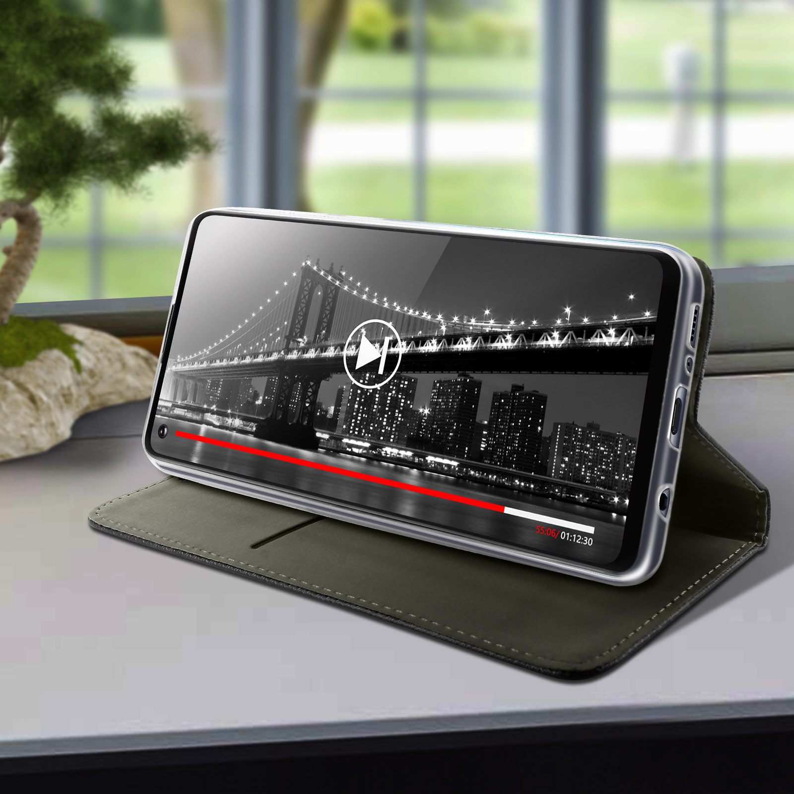Smartphone con video in riproduzione su un supporto, sfondo interno.