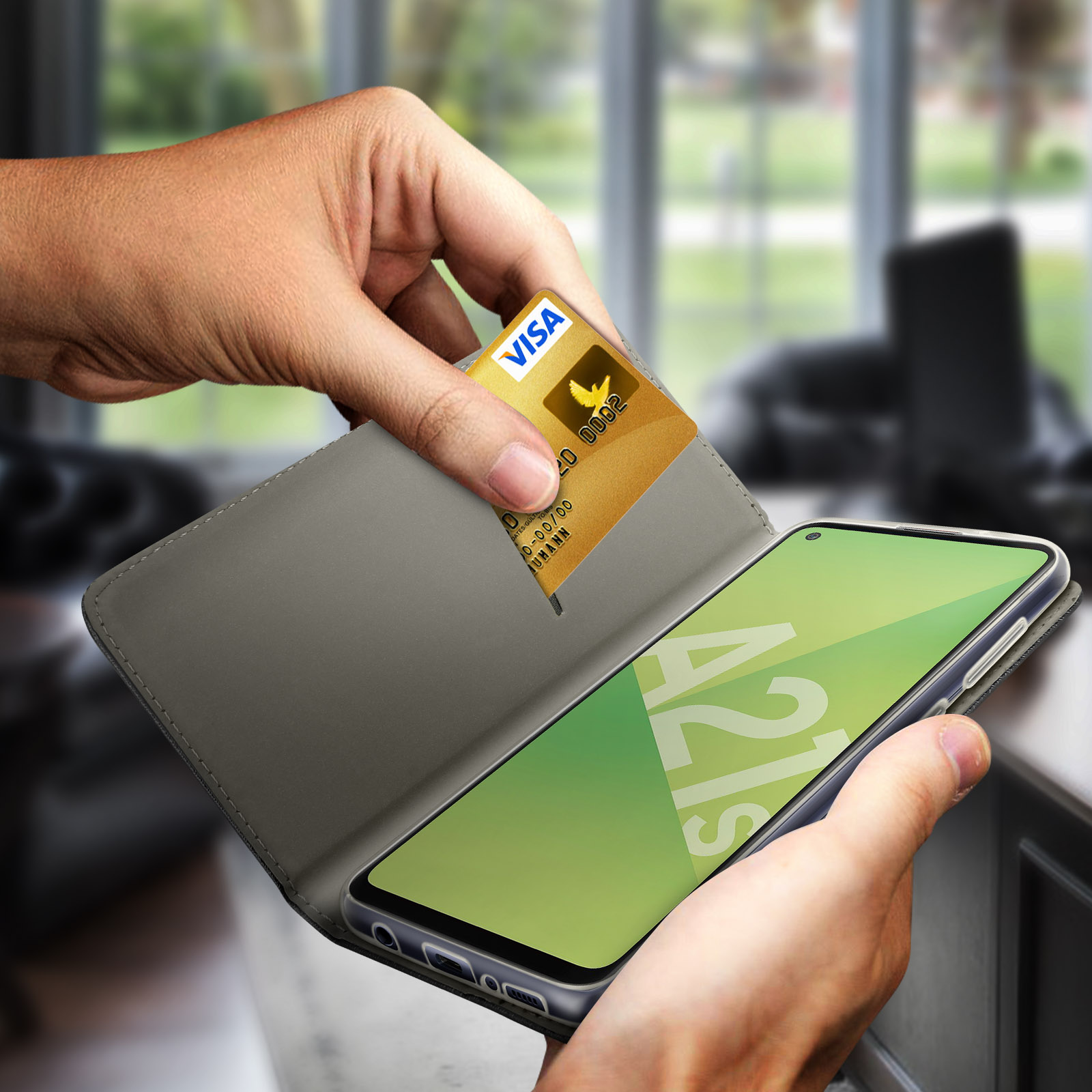 Mano che inserisce una carta Visa oro in una custodia grigia, vicino a un telefono.