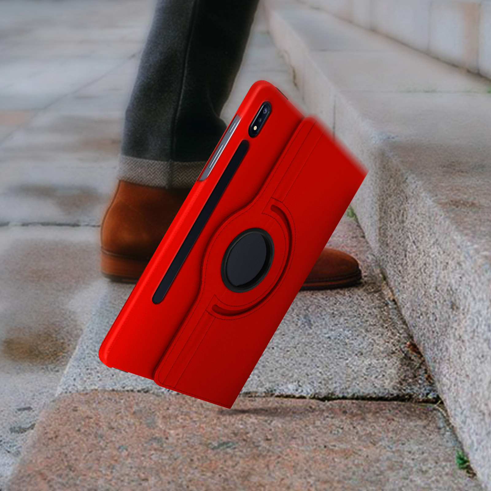 Custodia per telefono rossa tenuta su una scala. Dettaglio anello nero. Gambe e scarpe sullo sfondo.