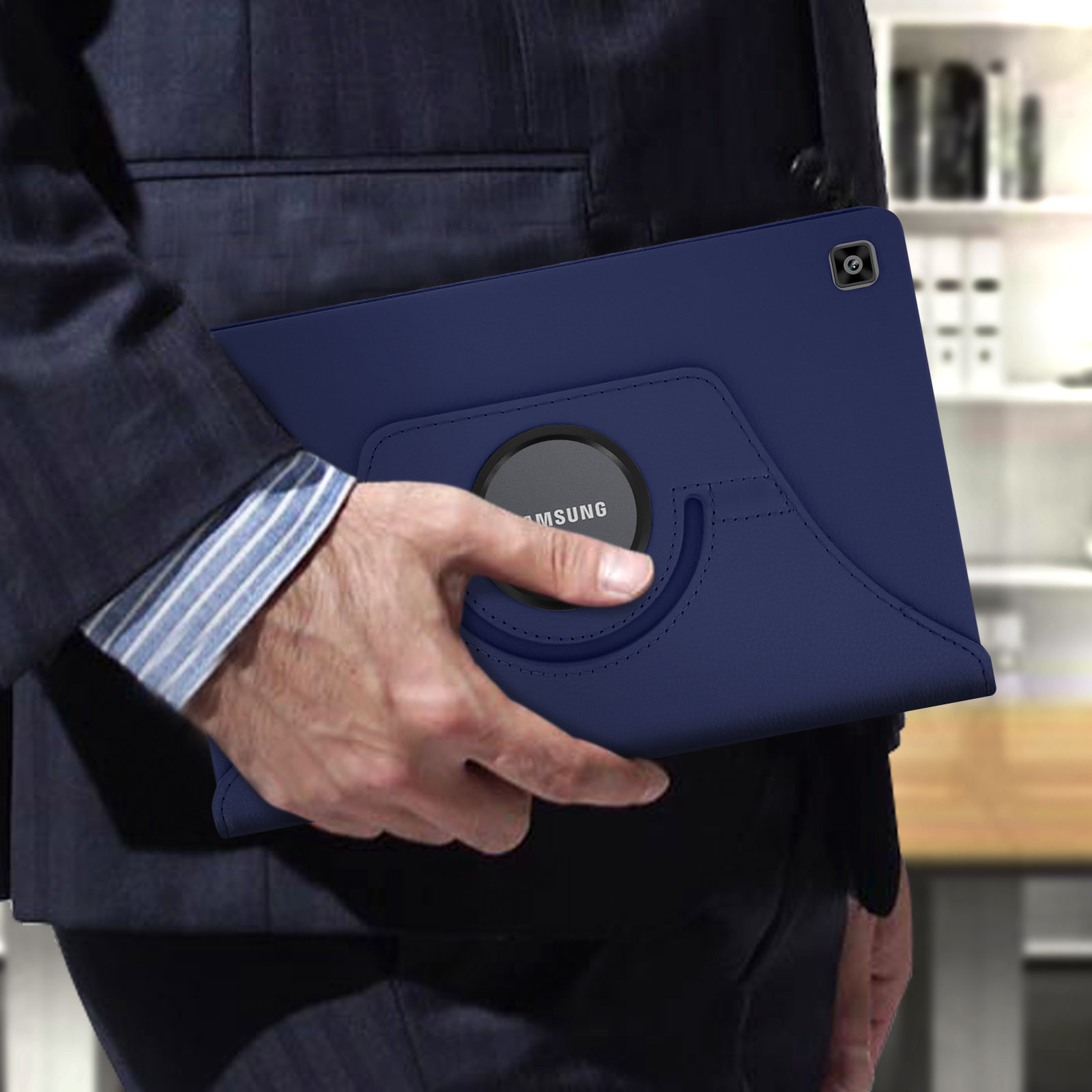Una persona che tiene una custodia blu per tablet con un anello rotante. La custodia è su un completo blu scuro.