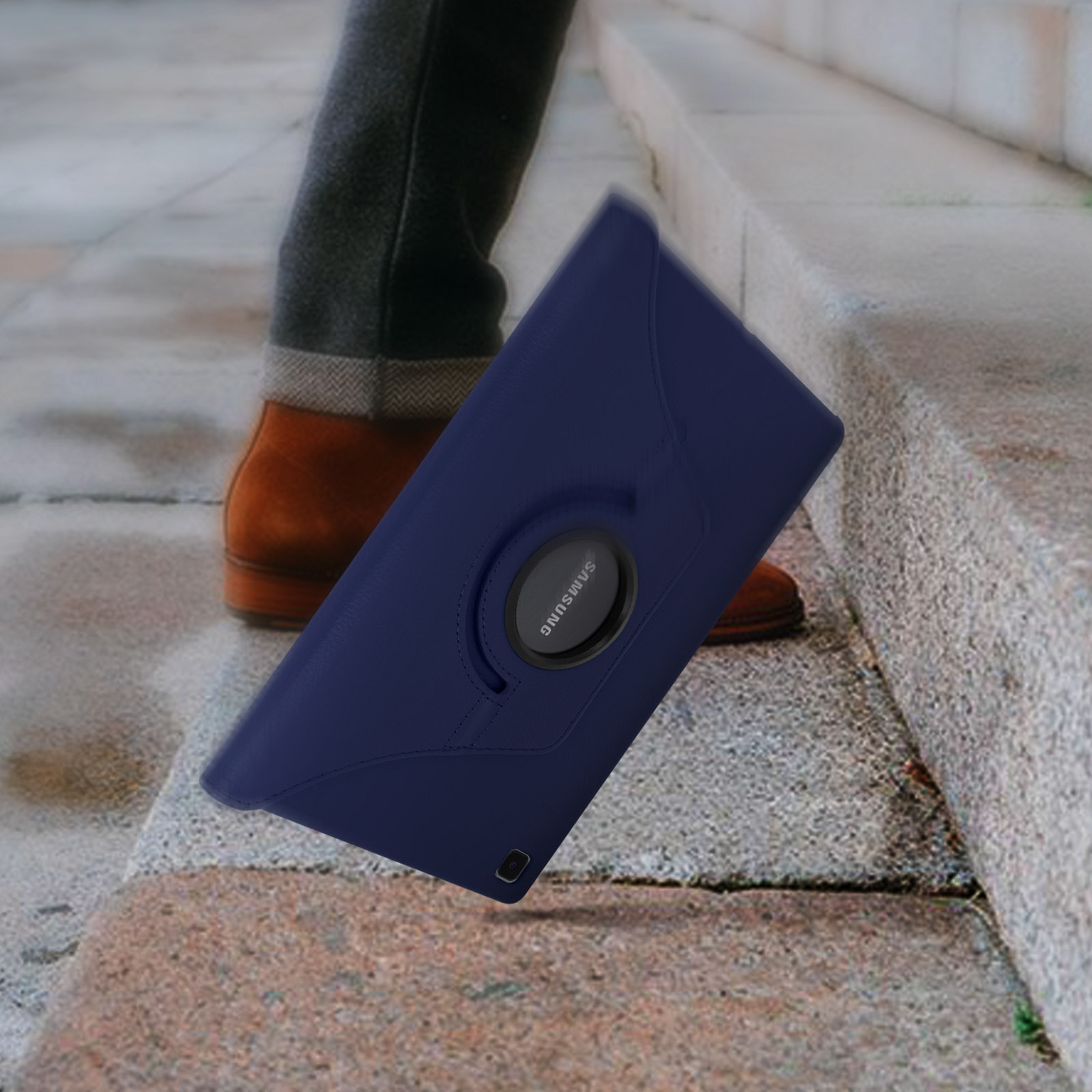 Una custodia per tablet blu con un anello rotante nero su un gradino, con una gamba e una scarpa sullo sfondo.