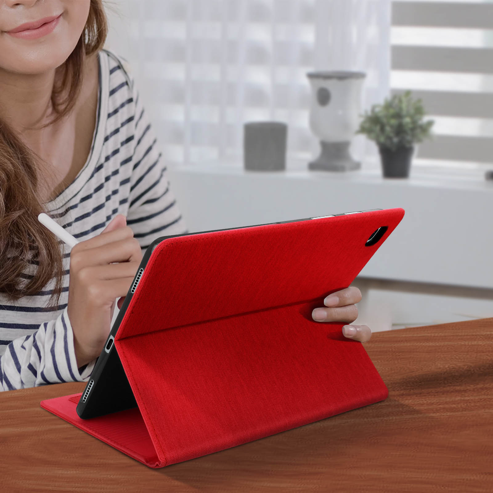 Una donna usa un tablet in una custodia rossa. Il tablet è appoggiato su una scrivania.