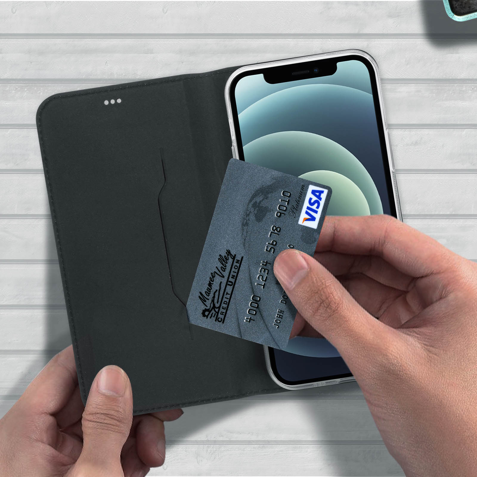 Mani che tengono una carta di credito accanto a un telefono dentro un portafoglio.