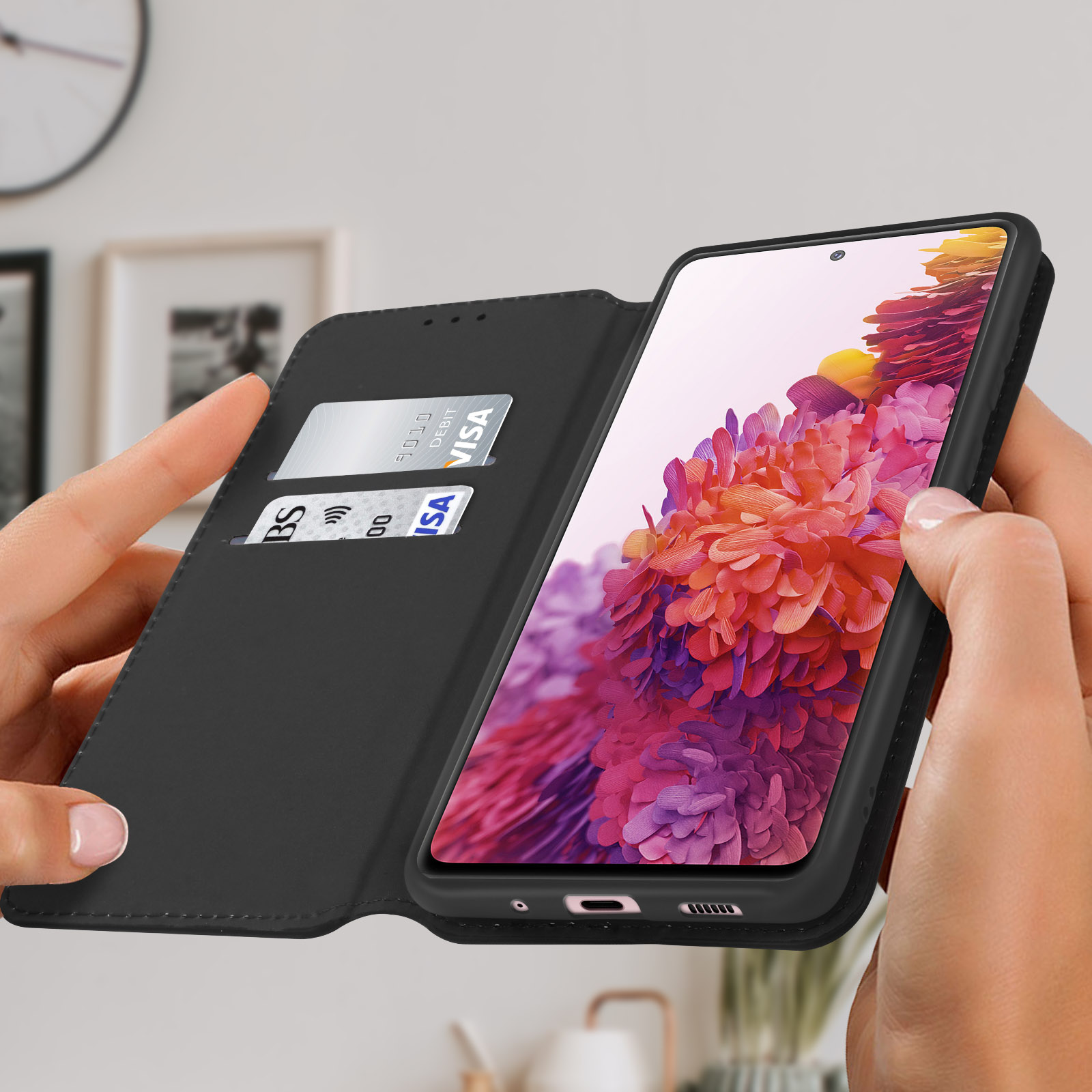 Eine schwarze Handyhülle ist geöffnet und zeigt einen Telefonbildschirm mit Blumendesign. Kreditkarten sind in einem Schlitz.