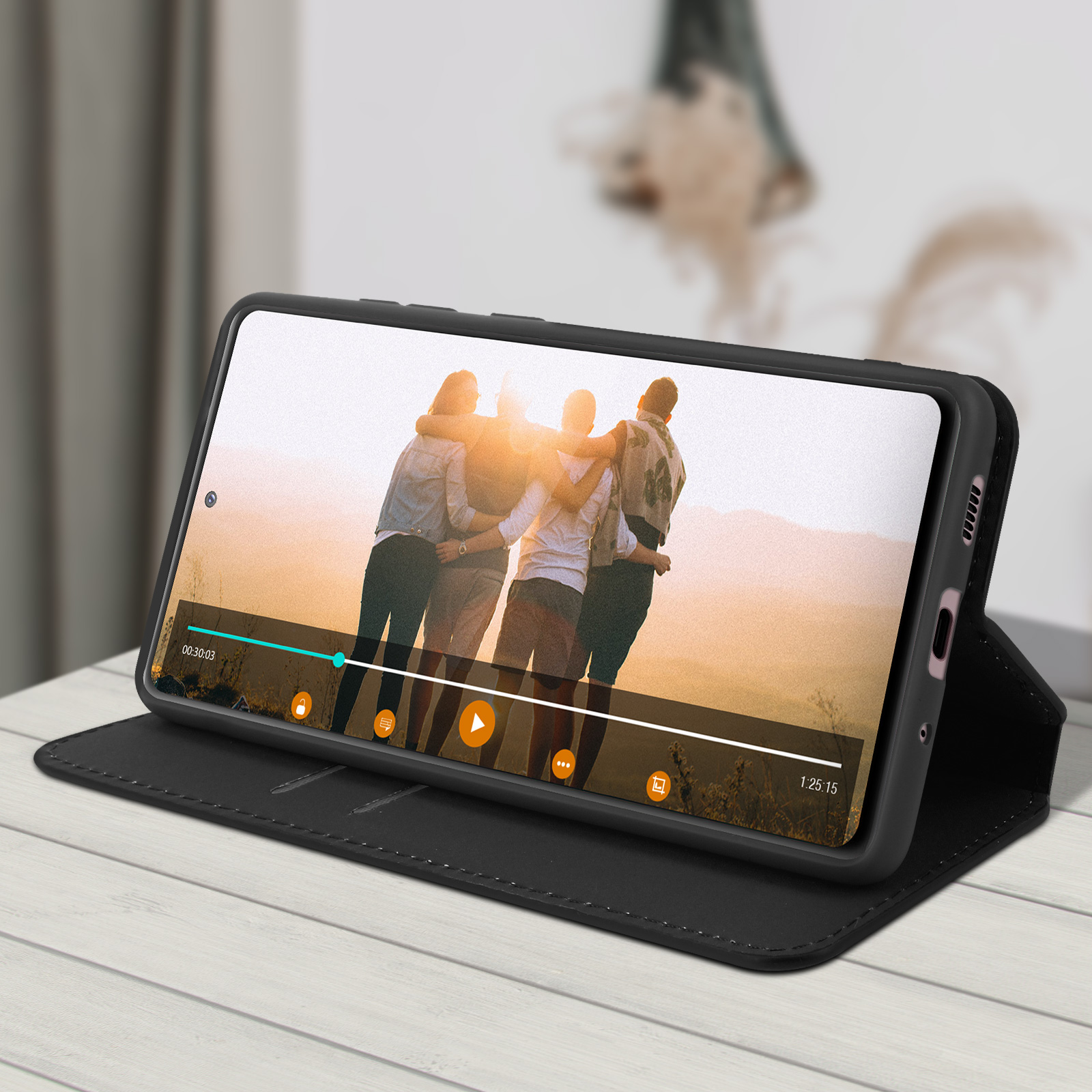 Ein schwarzes Telefon in einer Hülle zeigt ein Video. Die Hülle ist geöffnet und liegt auf einer Holzoberfläche.